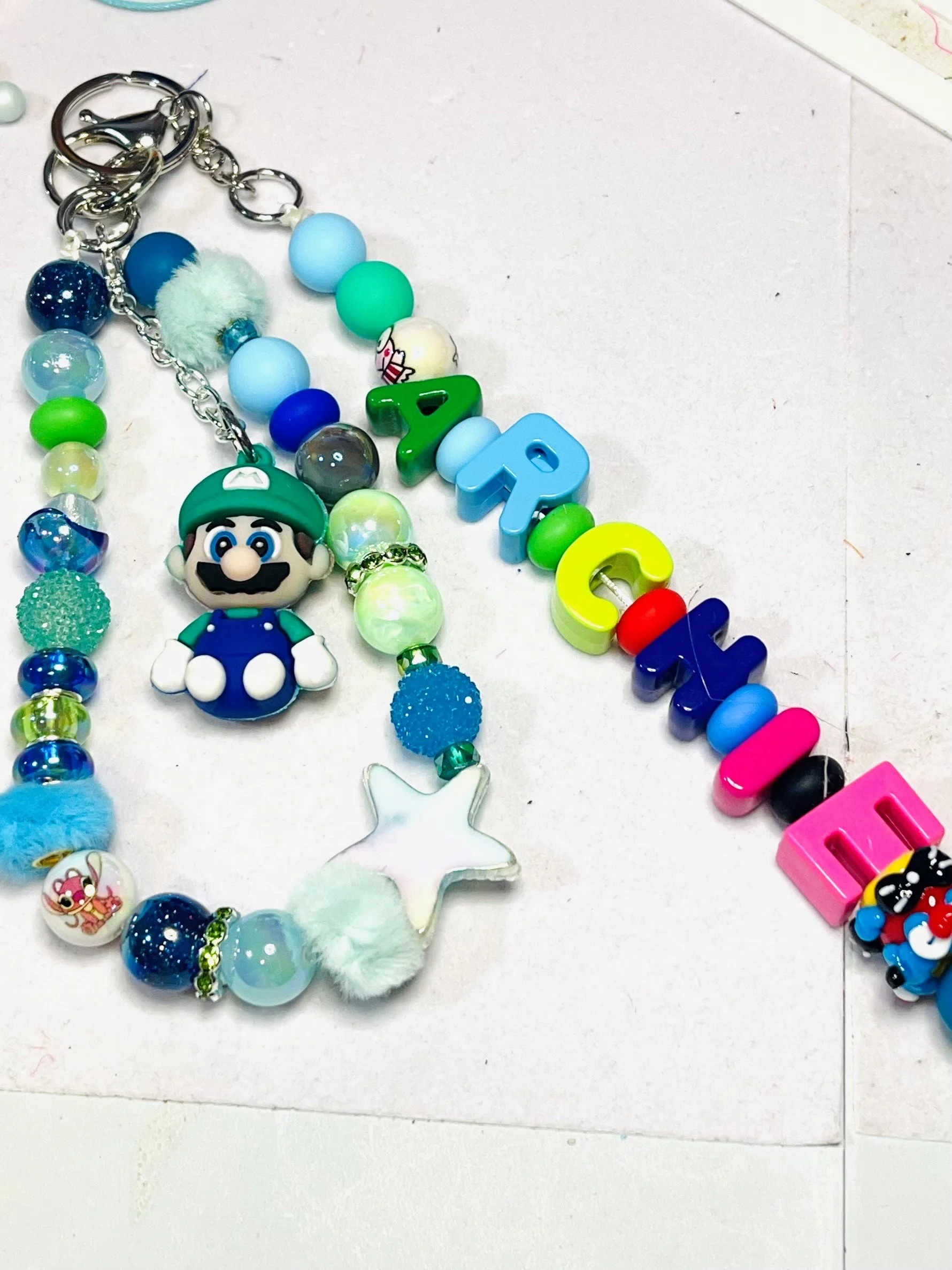 Colorful beaded necklace with characters from Super Mario and other decorative beads on a white background.