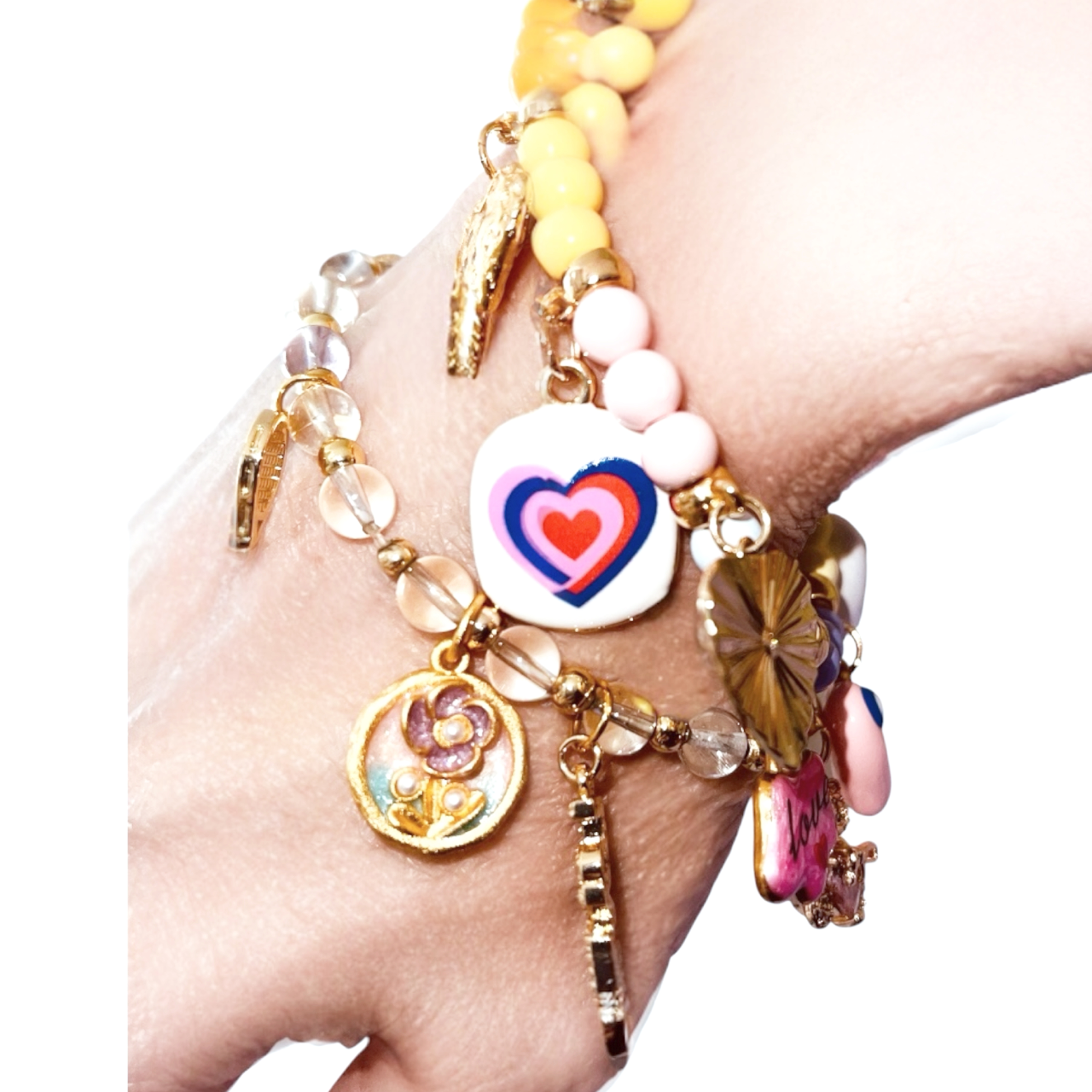 Multiple colorful charm bracelets on a person's wrist, featuring hearts, flowers, and various decorative beads. Charm Bar Idea