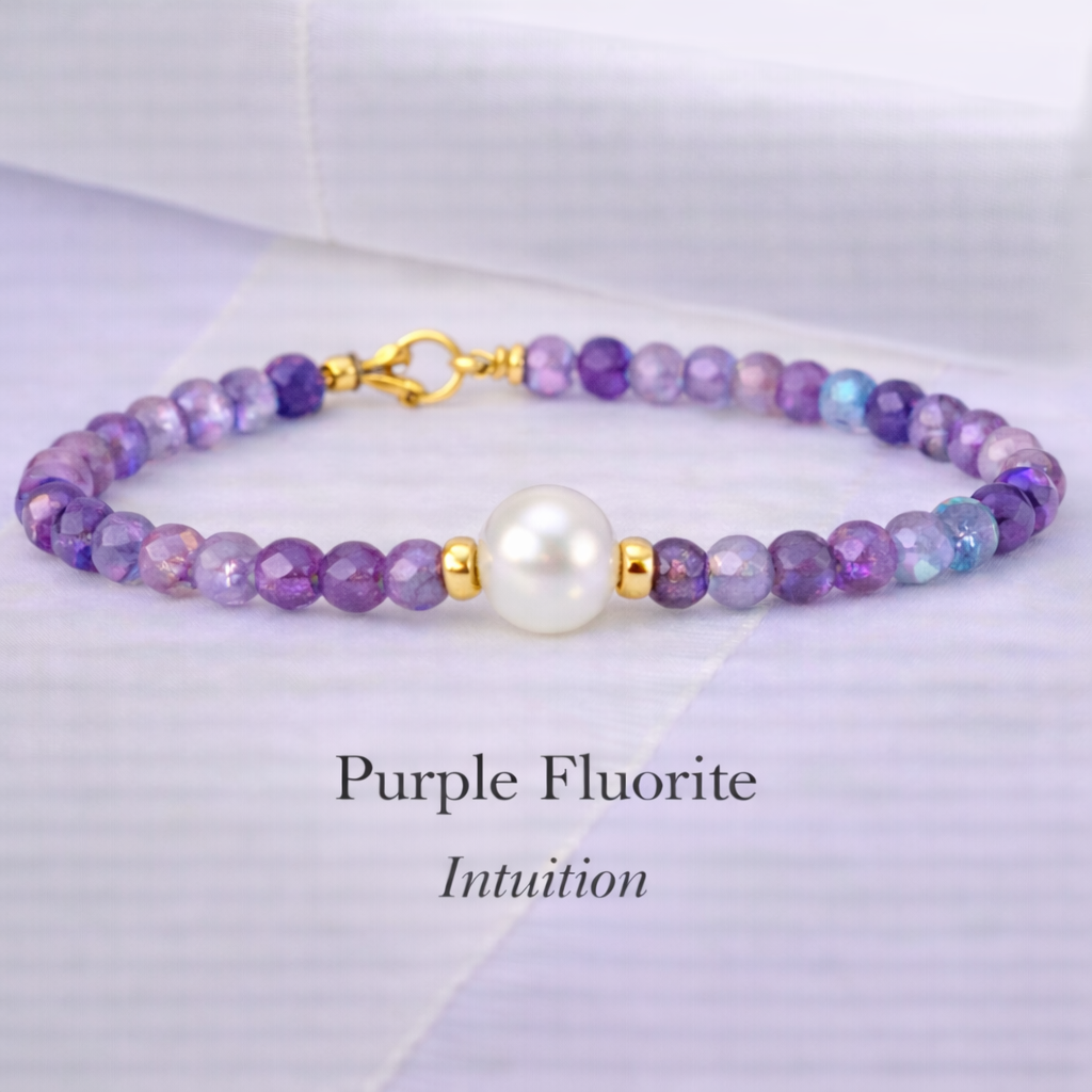 A beaded bracelet made of purple fluorite beads with a central white pearl and gold accents, laid on a soft pastel background. The text below reads 'Purple Fluorite' and 'Intuition'.
