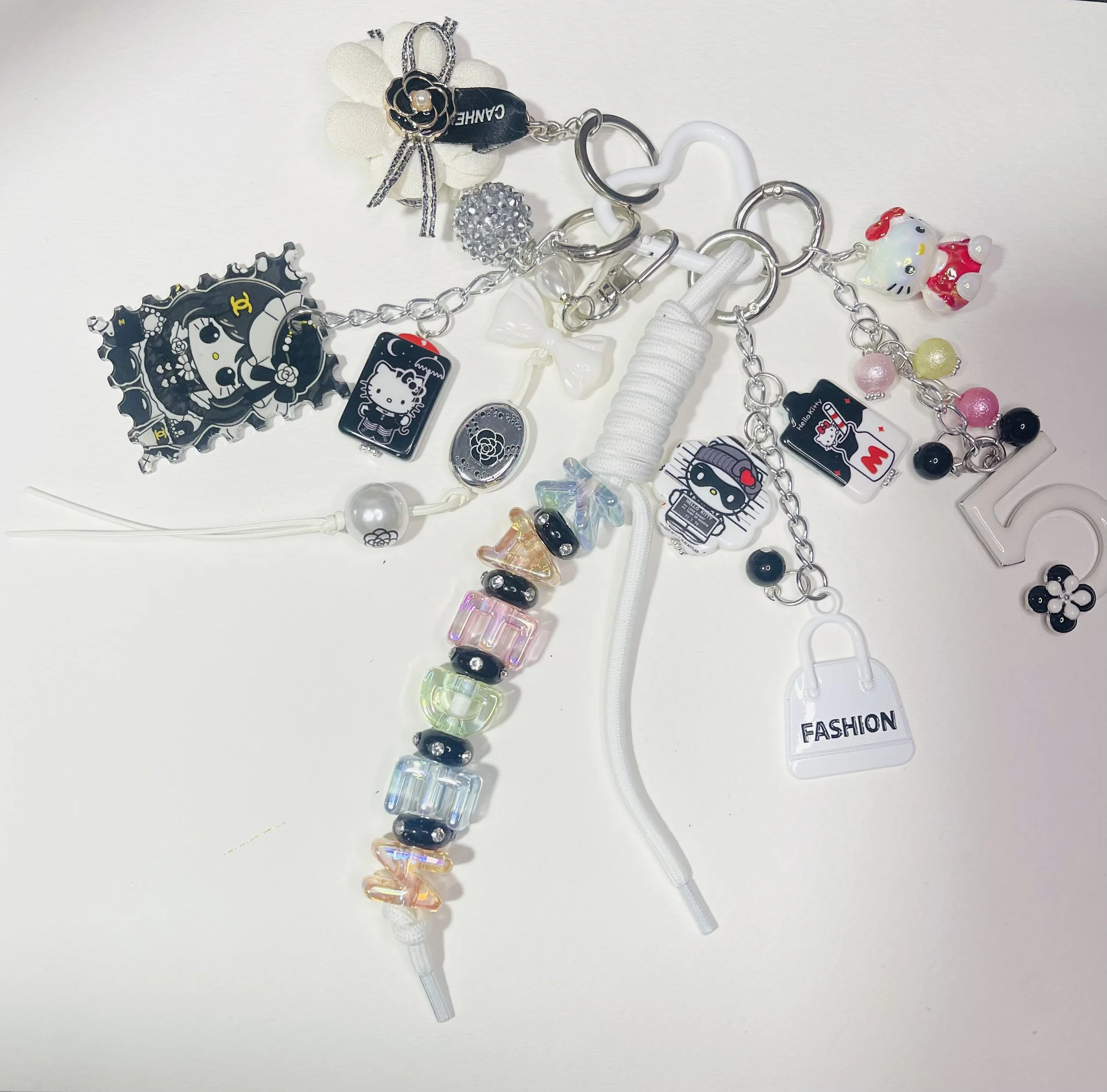 Assorted fashion accessories and jewelry items including charms, beads, and keychains on a white background.