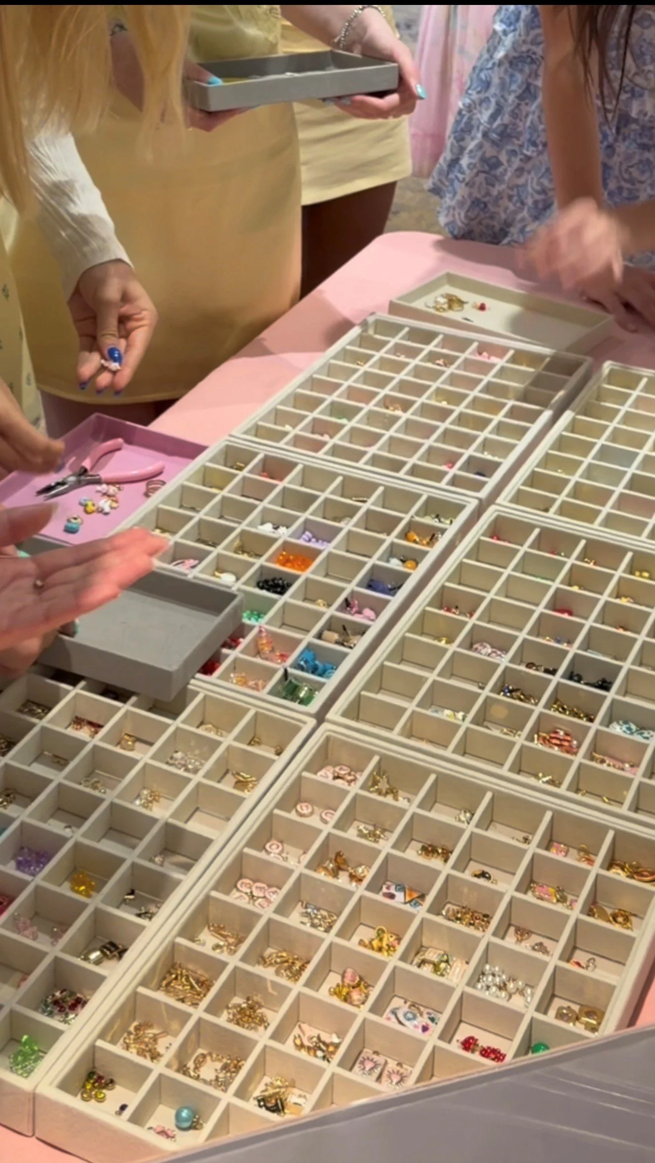 Several open jewelry boxes filled with a variety of rhinestone, pearl, and metal jewelry pieces, with some people selecting jewelry from the boxes.