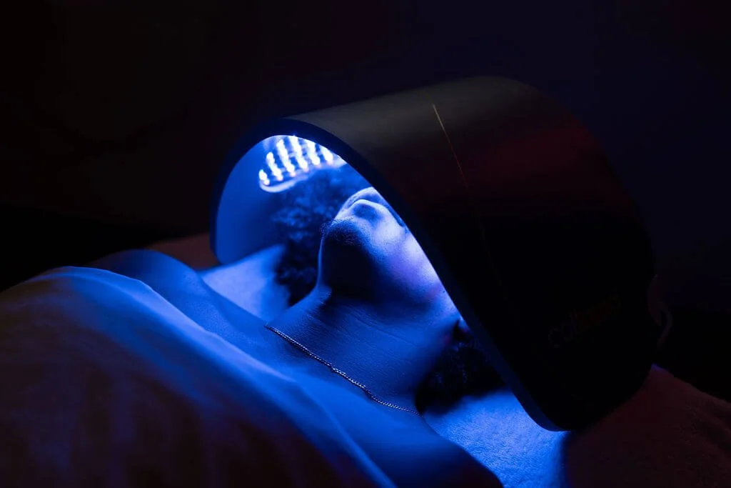 Person lying down under a UV light for teeth whitening treatment.