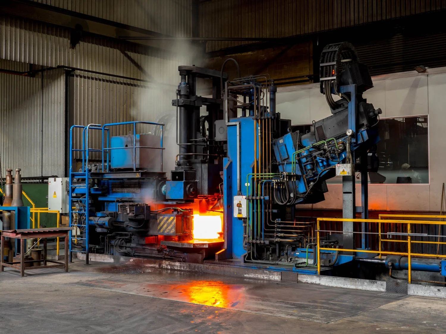 Industrial metal forging machine heating metal to high temperature in a factory setting.