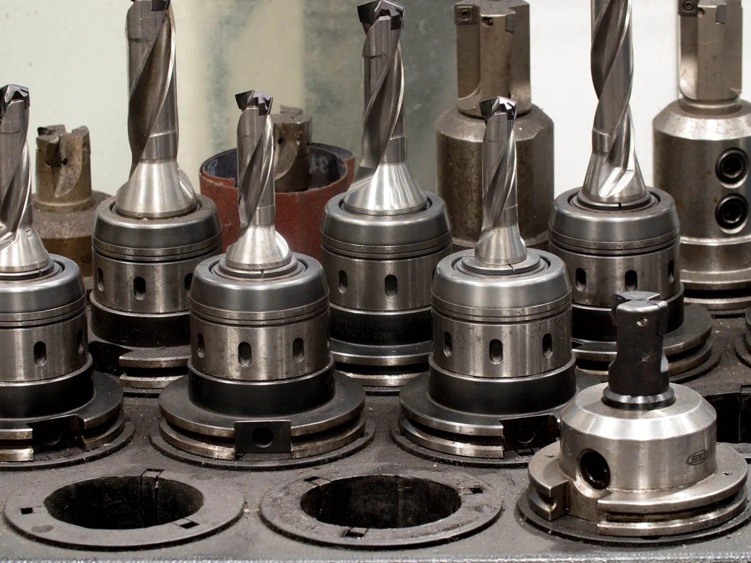 Various metal drill chucks and tool holders arranged on a workbench in a machining or manufacturing workshop.