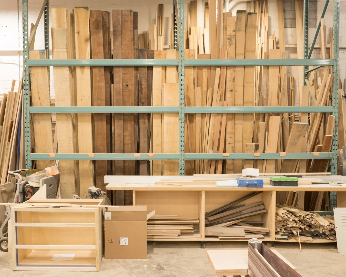 Wood storage shelves filled with various pieces of cut wood and planks in a woodworking workshop.