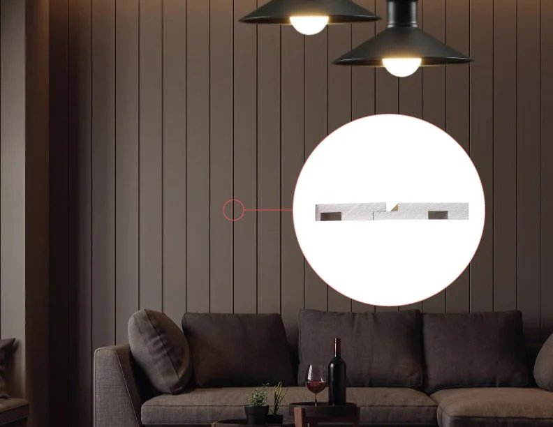 Living room with a gray couch, dark wood paneled wall, and three black pendant lights hanging from the ceiling. There is a close-up inset showing a white object on the wall, possibly a picture frame or artwork.