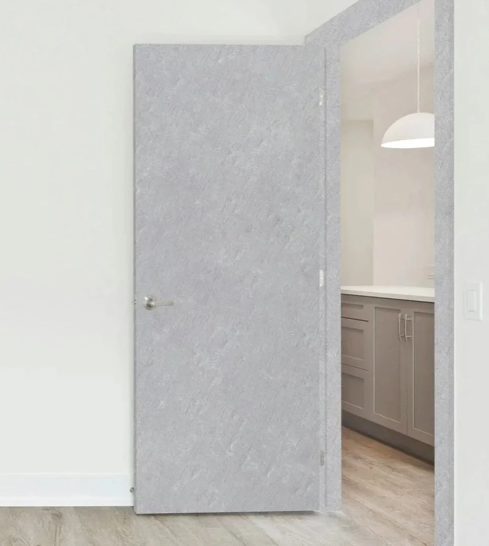 Gray textured door partially open revealing a kitchen with light gray cabinets and a white countertop, pendant light hanging from the ceiling.