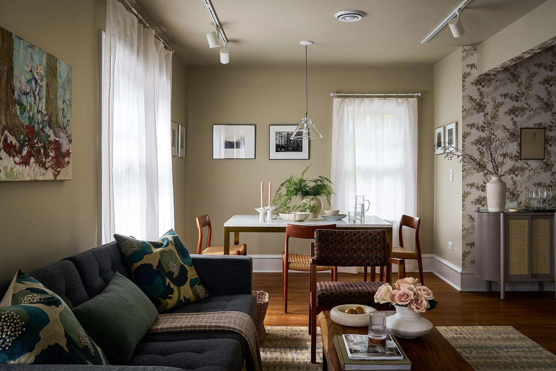Living room with a sitting area, a dining table with chairs, artwork, and decorative items.