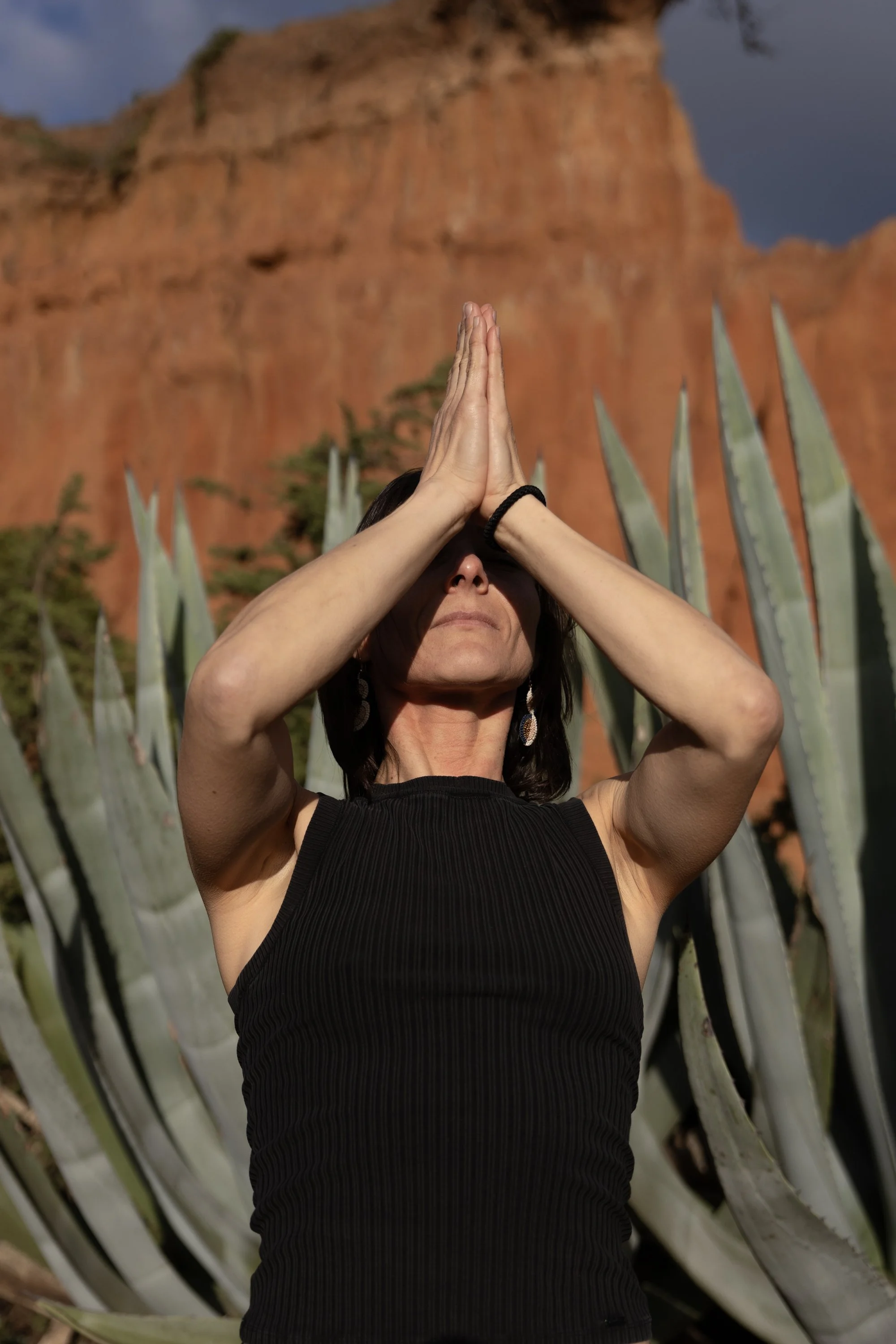 Woman practicing yoga outdoors with mountains and agave plants in the background