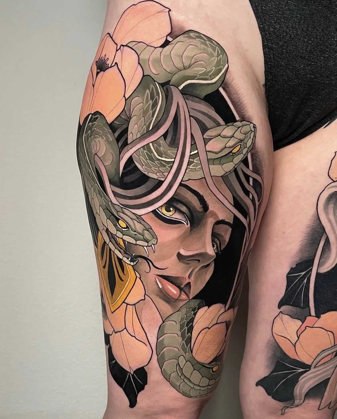 Tattoo of a woman's face intertwined with a snake and surrounded by flowers.