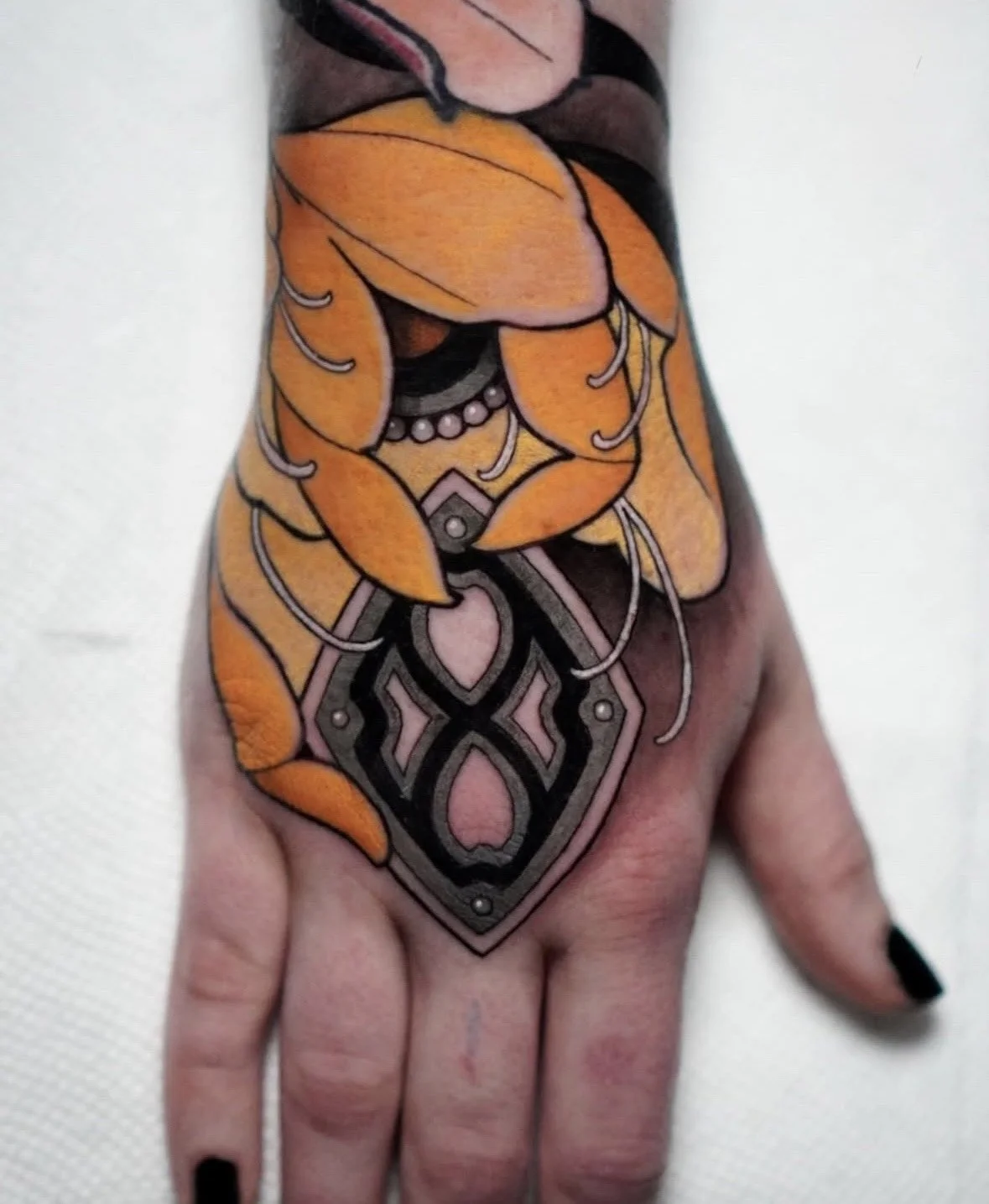 Colorful tattoo of a woman's face with orange hair and black jewelry on the hand.