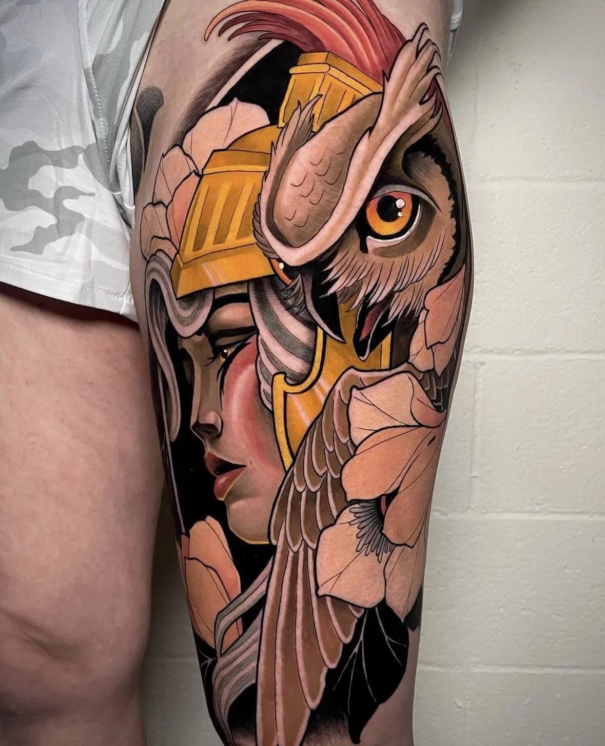 Tattoo of a woman's face with closed eyes, a large owl with one eye visible, and beige leaves surrounding the figures.