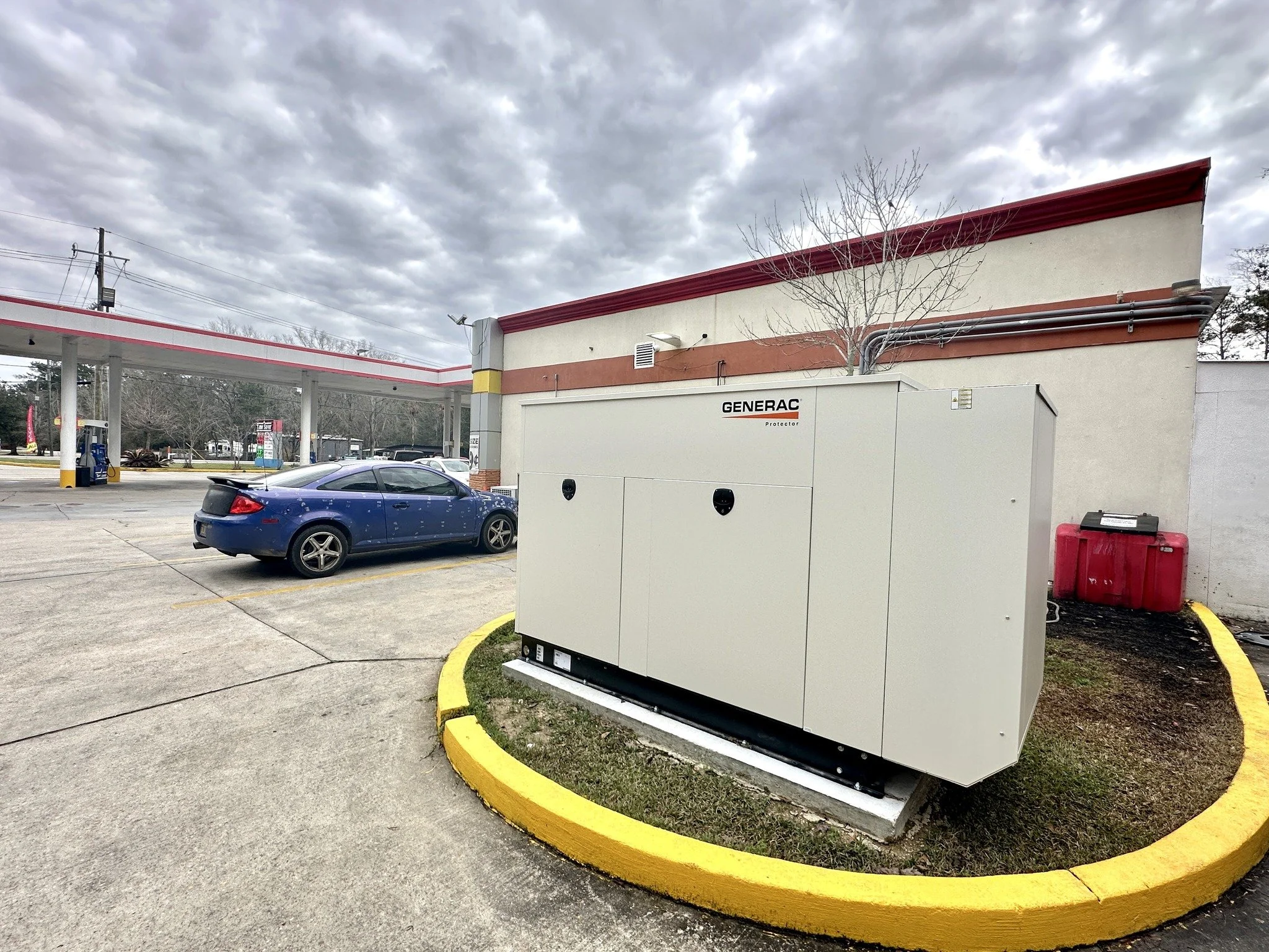 A Generac generator installed outside a convenience store with a red and white canopy, a blue car parked nearby, and a cloudy sky overhead.
