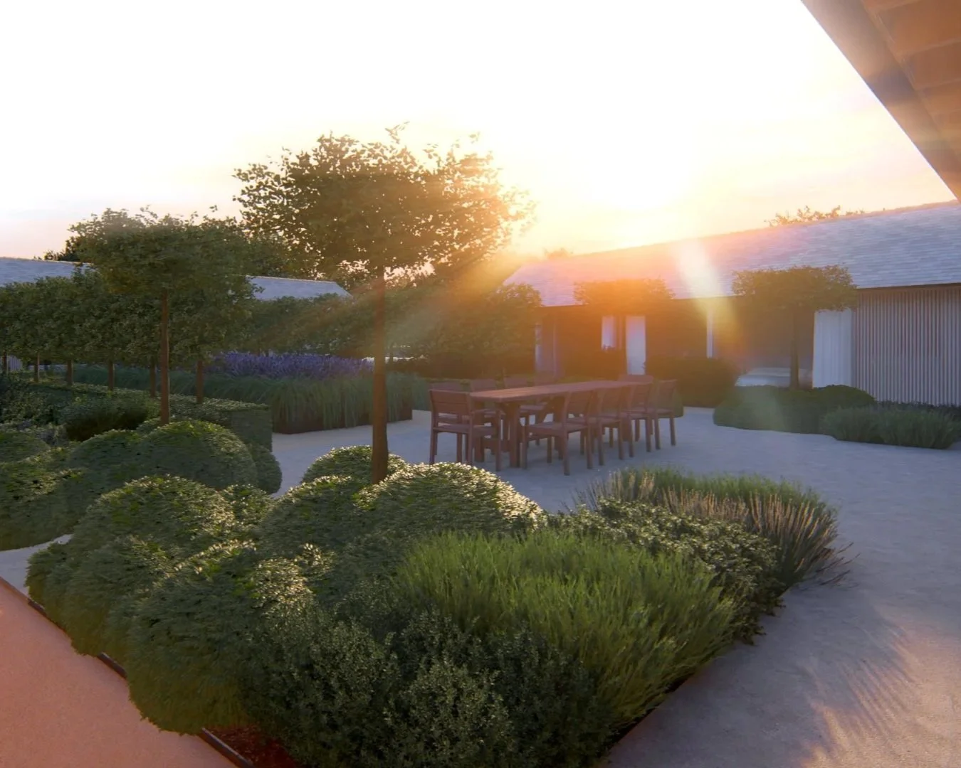 An outdoor patio with a wooden dining table and chairs, surrounded by lush green bushes and small trees, under a bright setting sun.