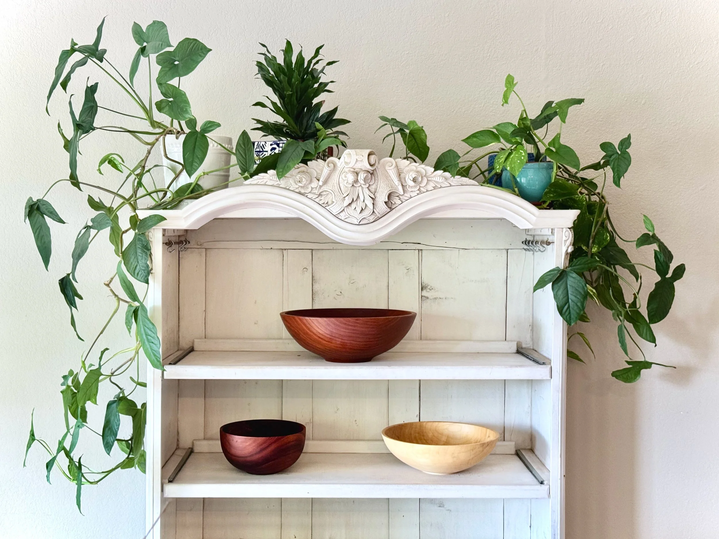 Antique white wardrobe refinished and repurposed as an open-face pantry, featuring custom pullout shelves and hand-turned wooden bowls made from reclaimed wood.