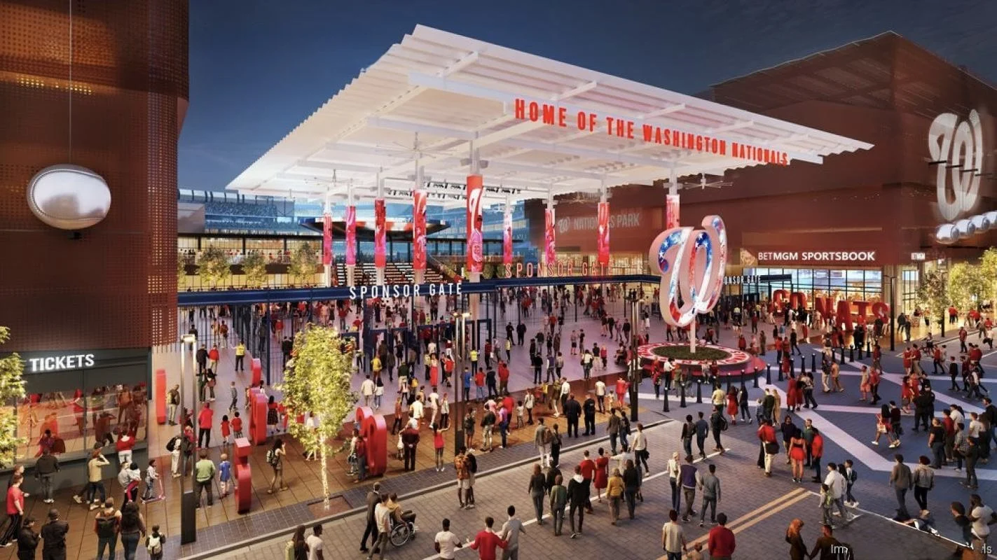 A busy outdoor entrance area to a sports stadium, with a large crowd of people walking and gathering.