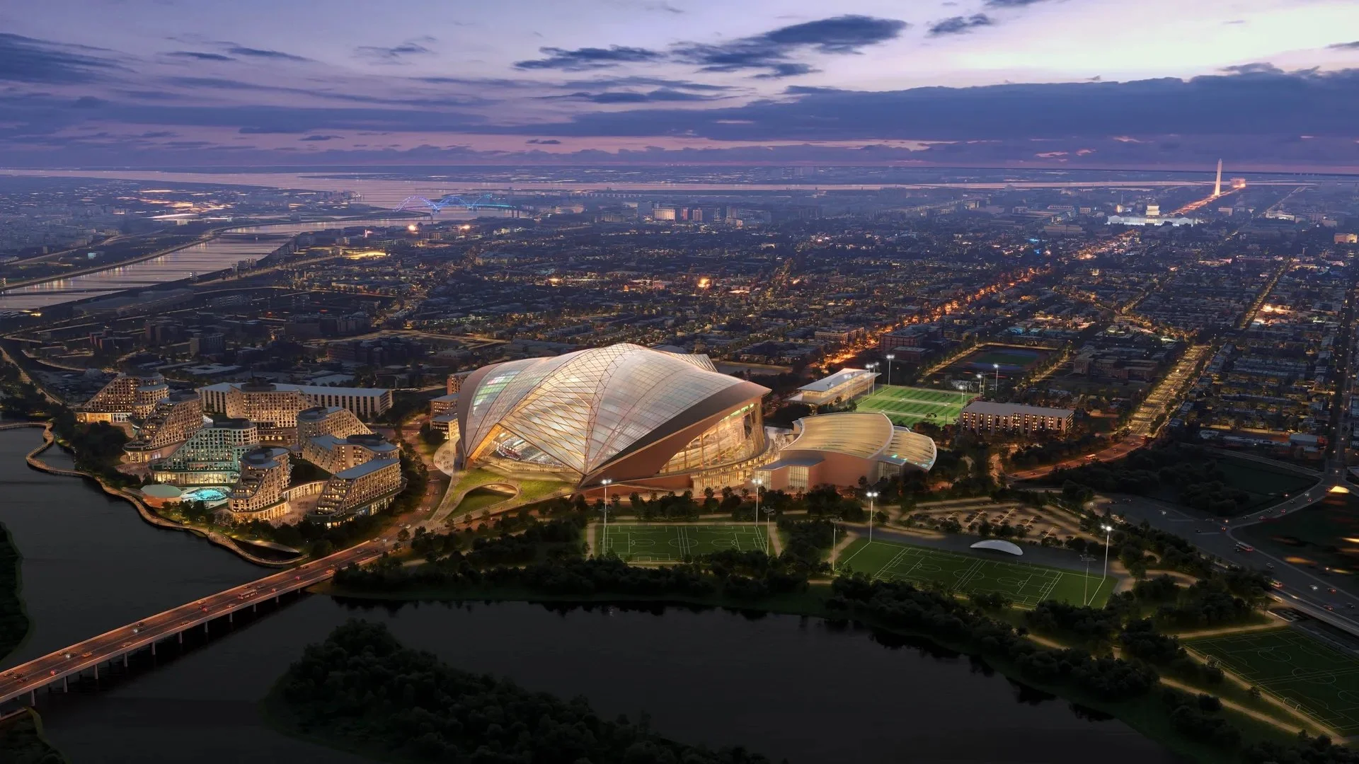 Aerial night view of a modern sports complex with illuminated football fields.