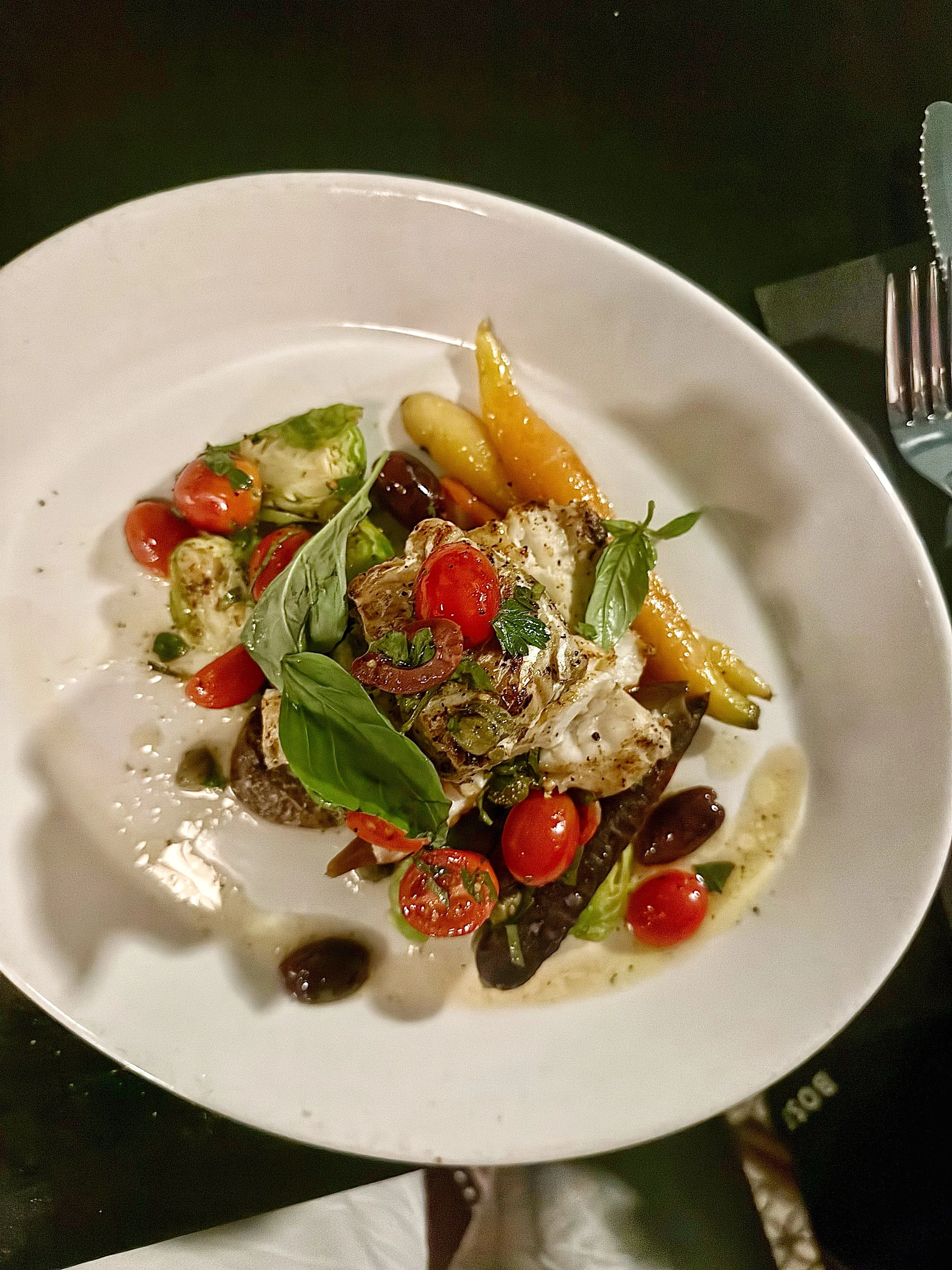 A gourmet seafood dish with cherry tomatoes, basil, and roasted vegetables on a white plate. ottawa best restaurants in westboro. westboro eats westboro foodies 