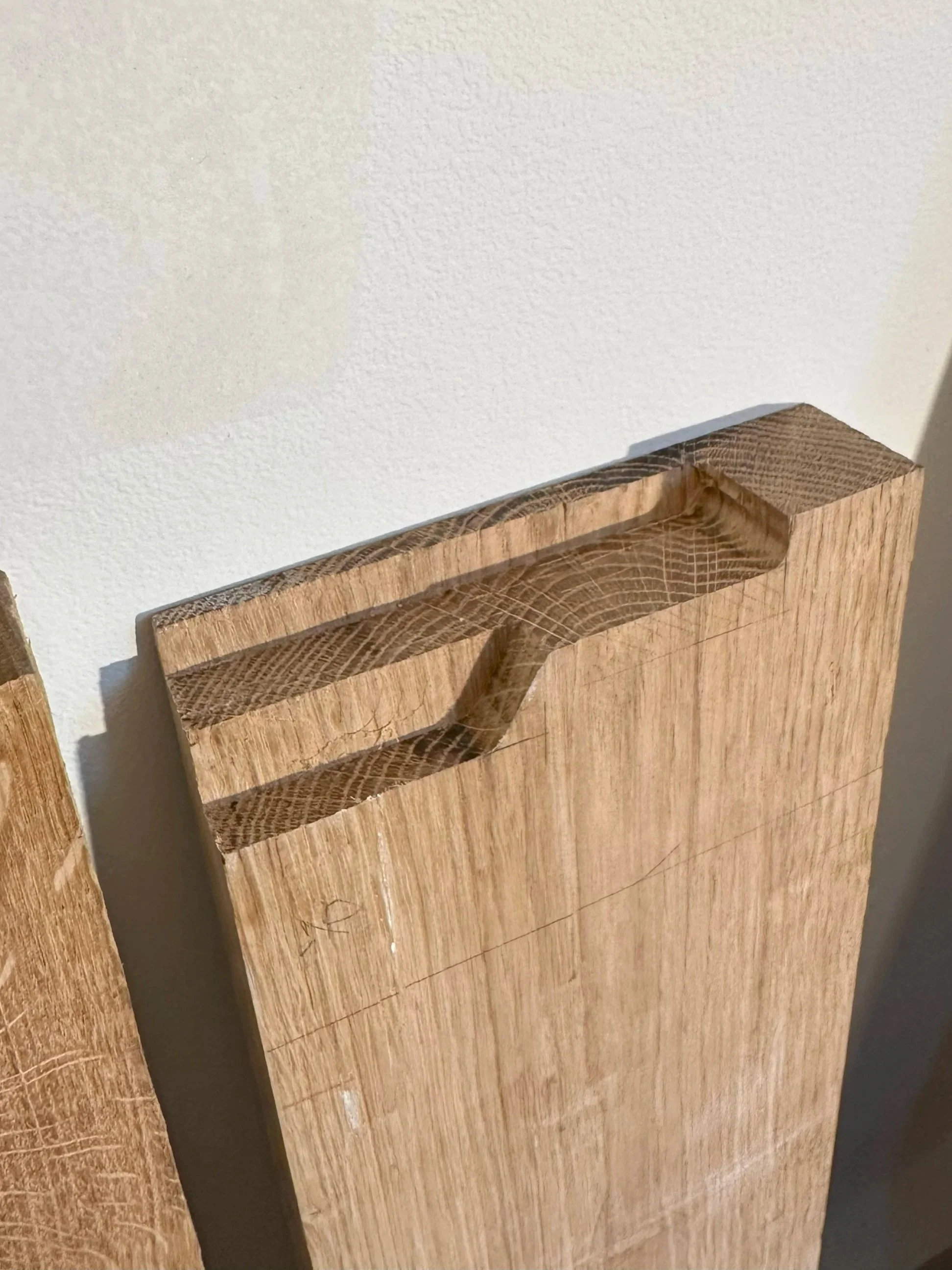 Close-up of a piece of wood with a carved groove, leaning against a wall.