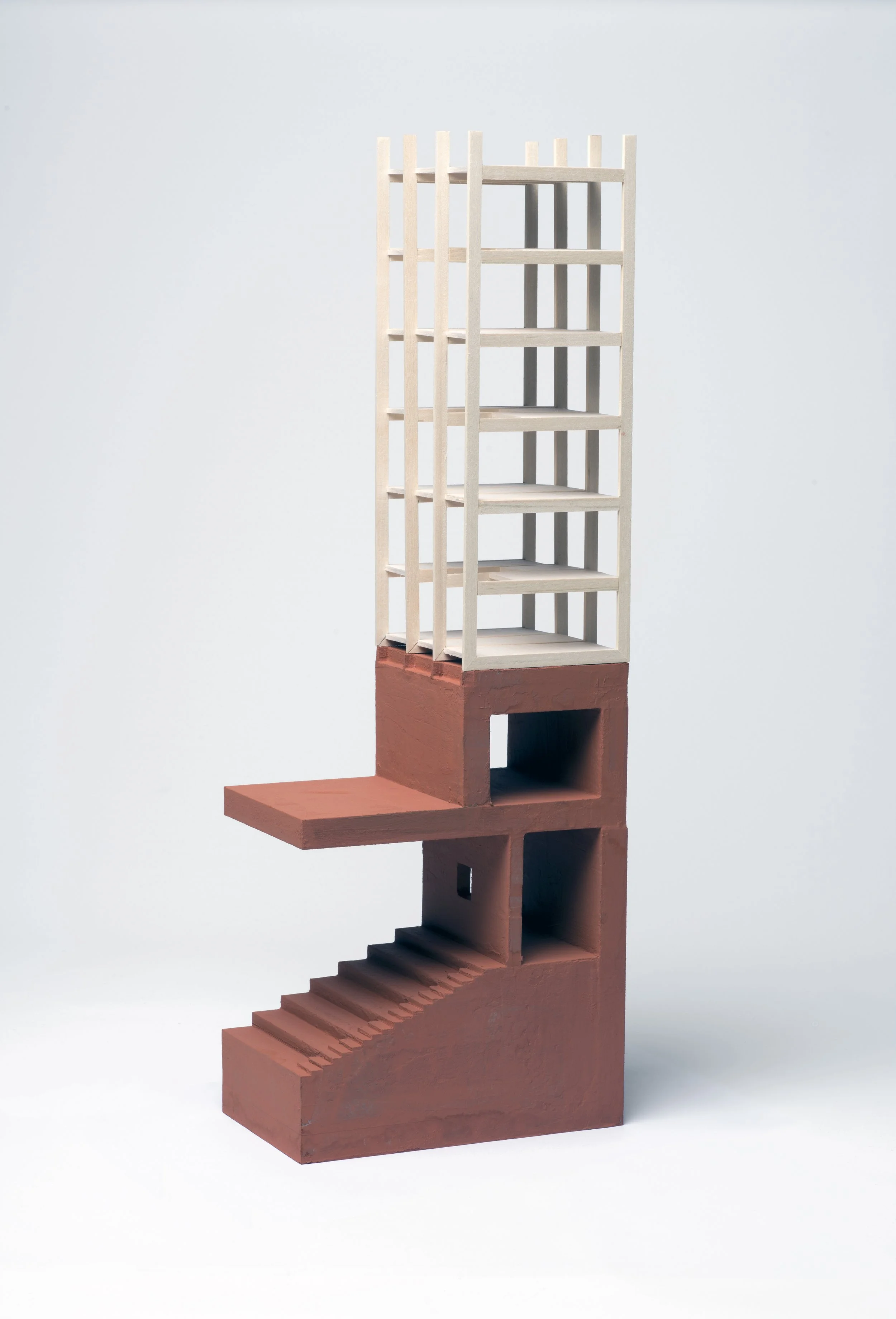 Architectural model featuring a multi-level structure with stairs, a platform, and a tall wooden framework against a light background.