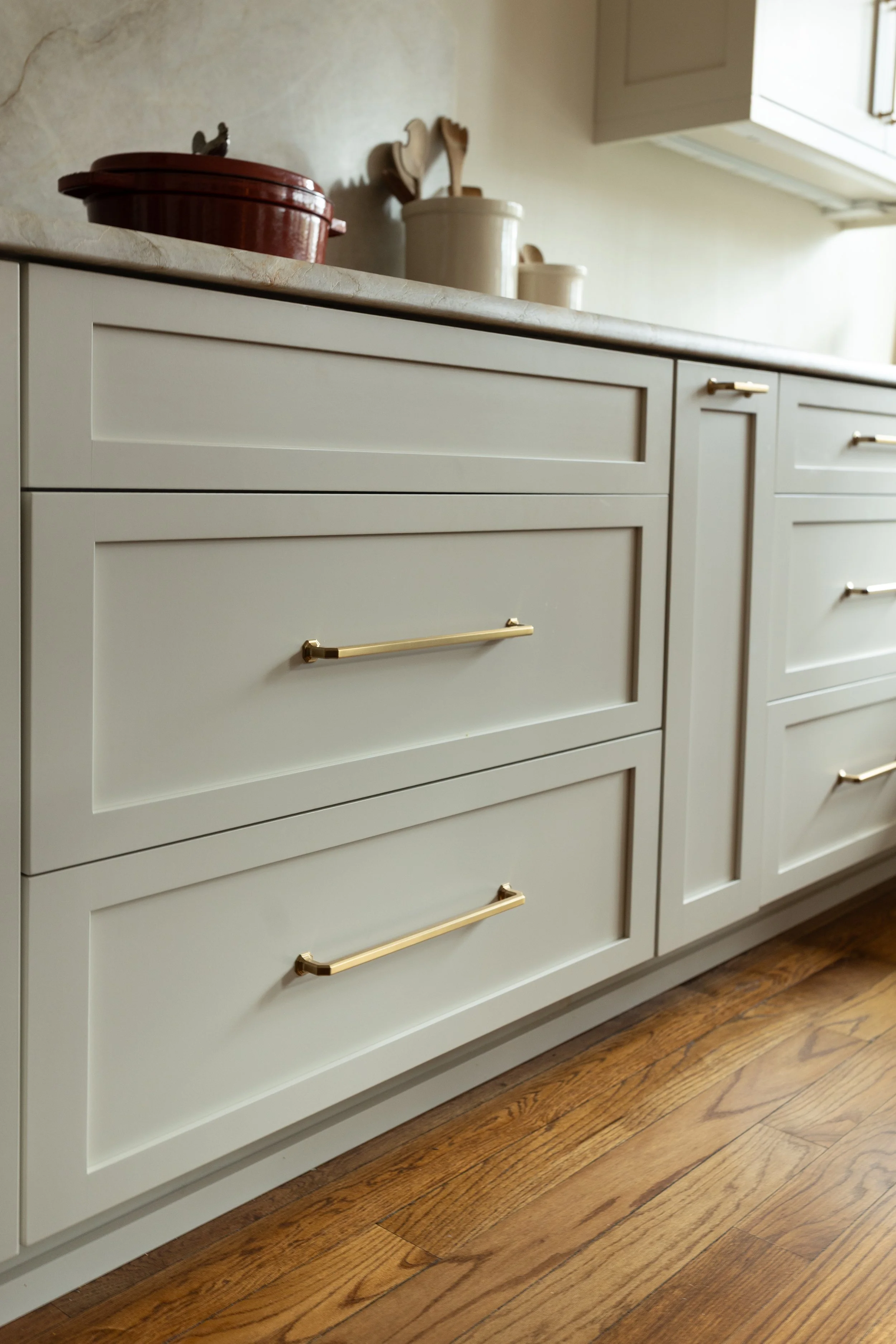 Polished brass hardware brings a subtle warmth and reflective quality to the cabinetry. The streamlined pulls balance classic design with a modern edge.