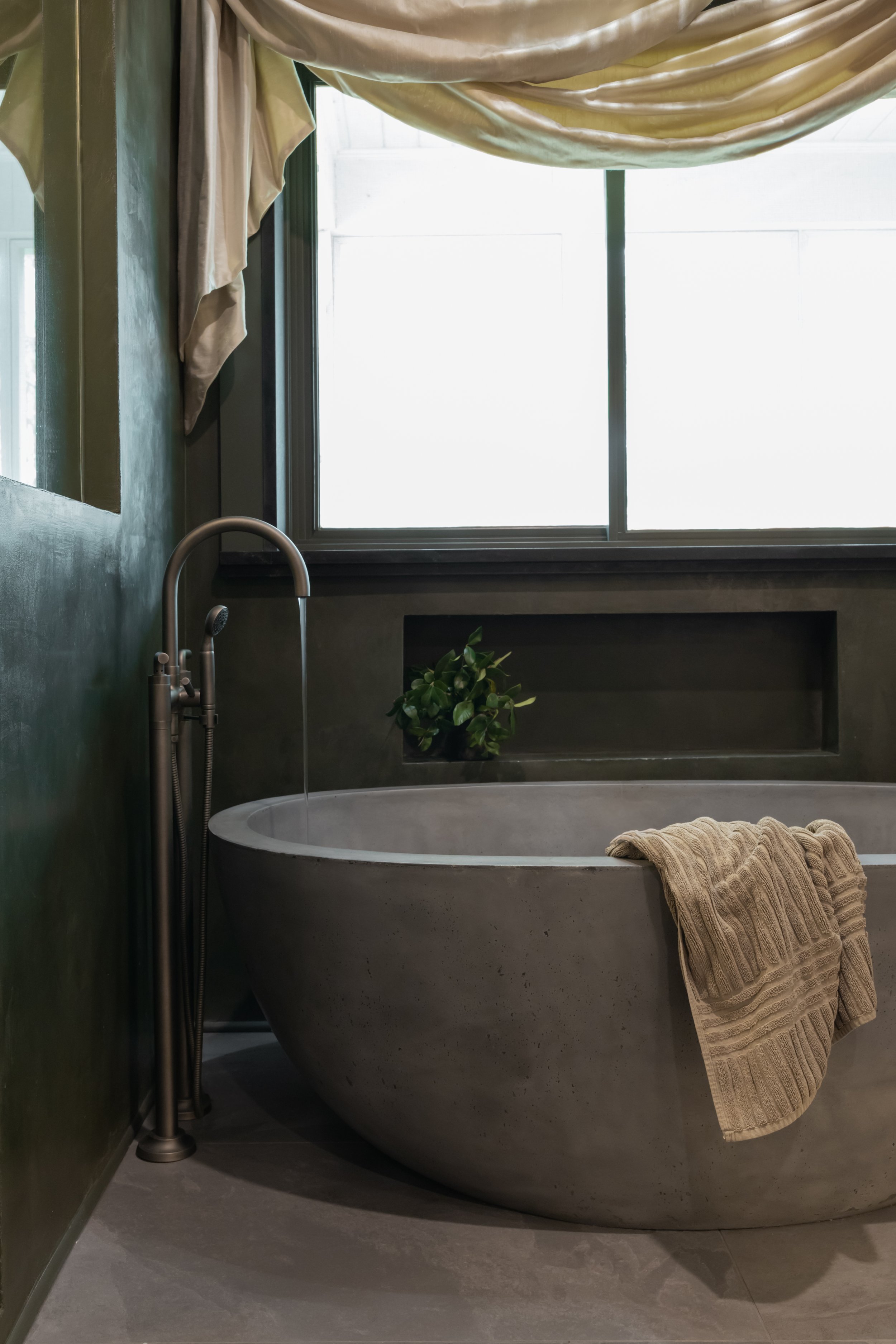 The freestanding stone soaking tub features a smooth, sculptural silhouette and deep basin, creating a spa-like focal point that enhances the luxury bathroom design while encouraging relaxation and everyday wellness.