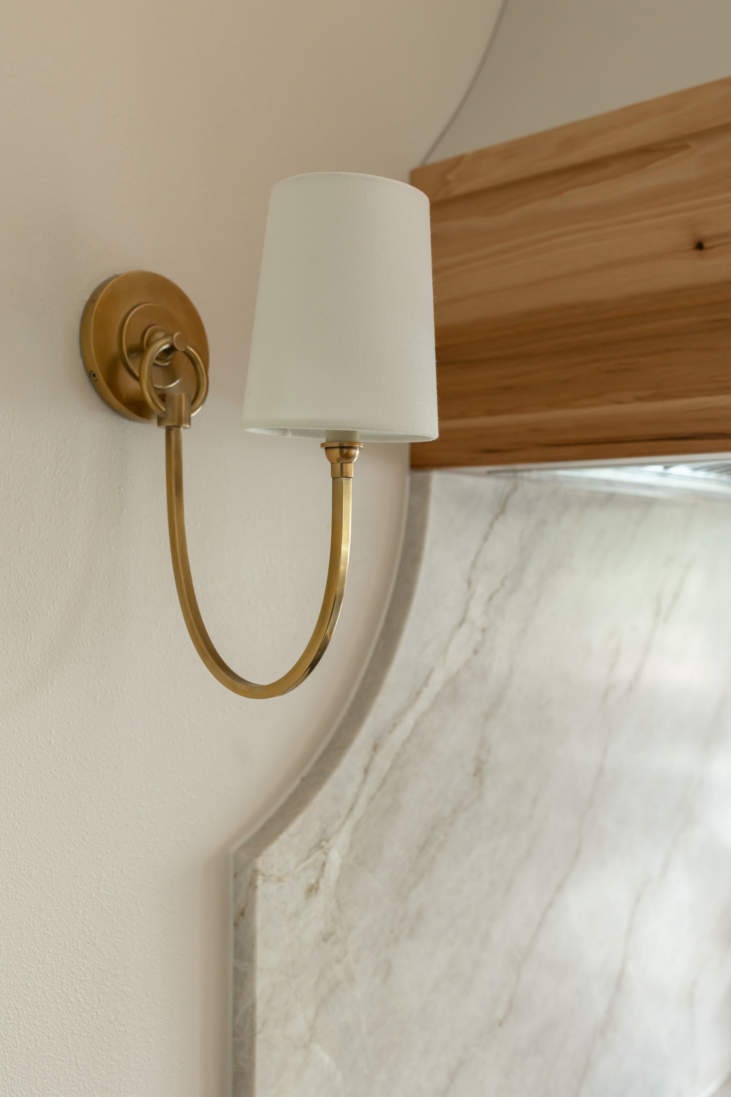 Sculptural pendant lights with white shades and brass detailing hang above the island, adding both function and visual interest.