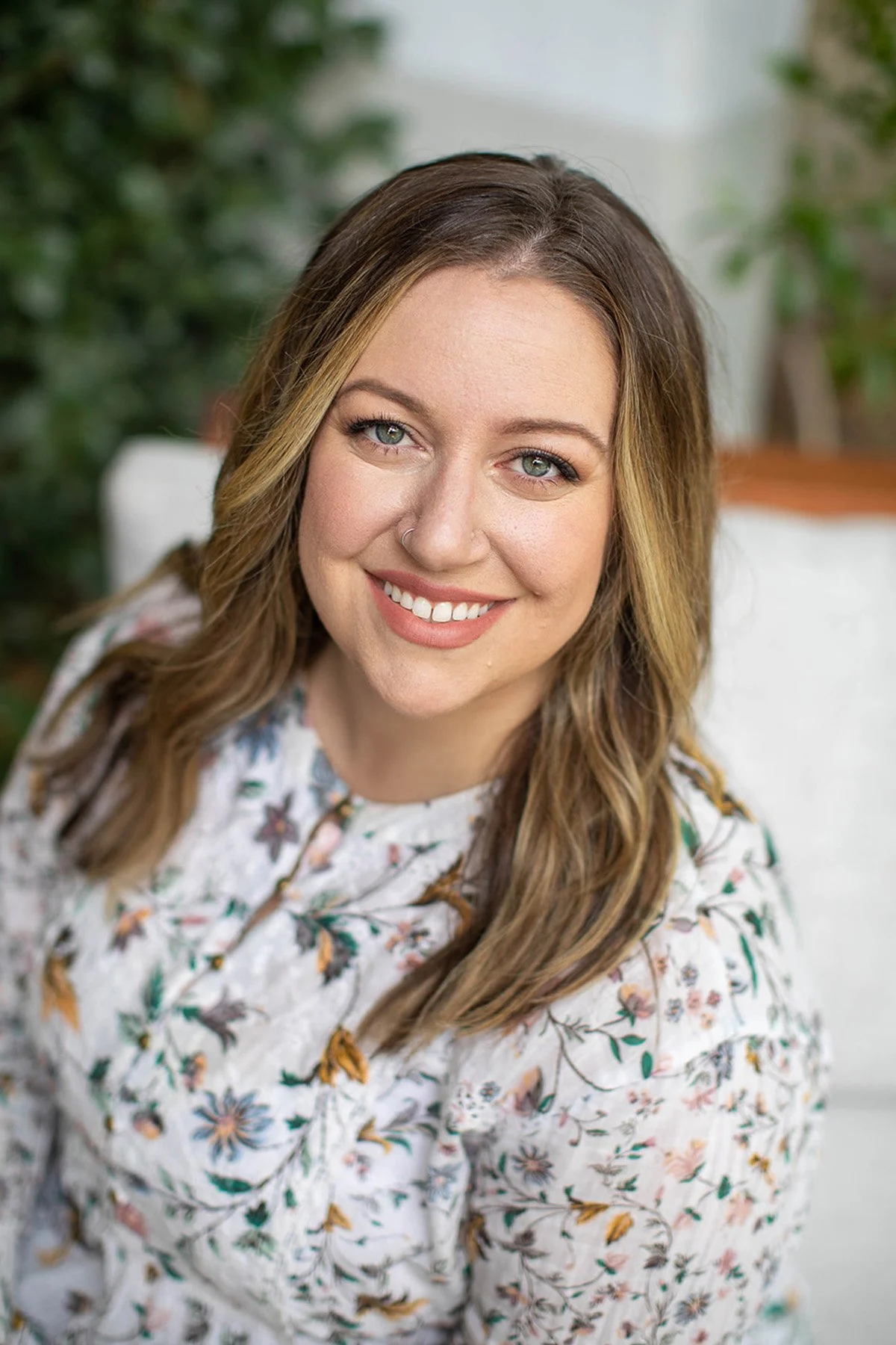 City Mom Media co-founder Lauren Stockard smiling while sitting outside in a floral blouse.