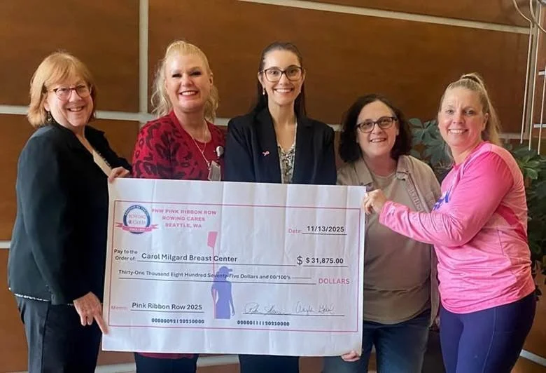 Five women holding a large check for $31,875 presented to Carol Milgard Breast Center, dated 11/13/2025, celebrating a fundraising event.