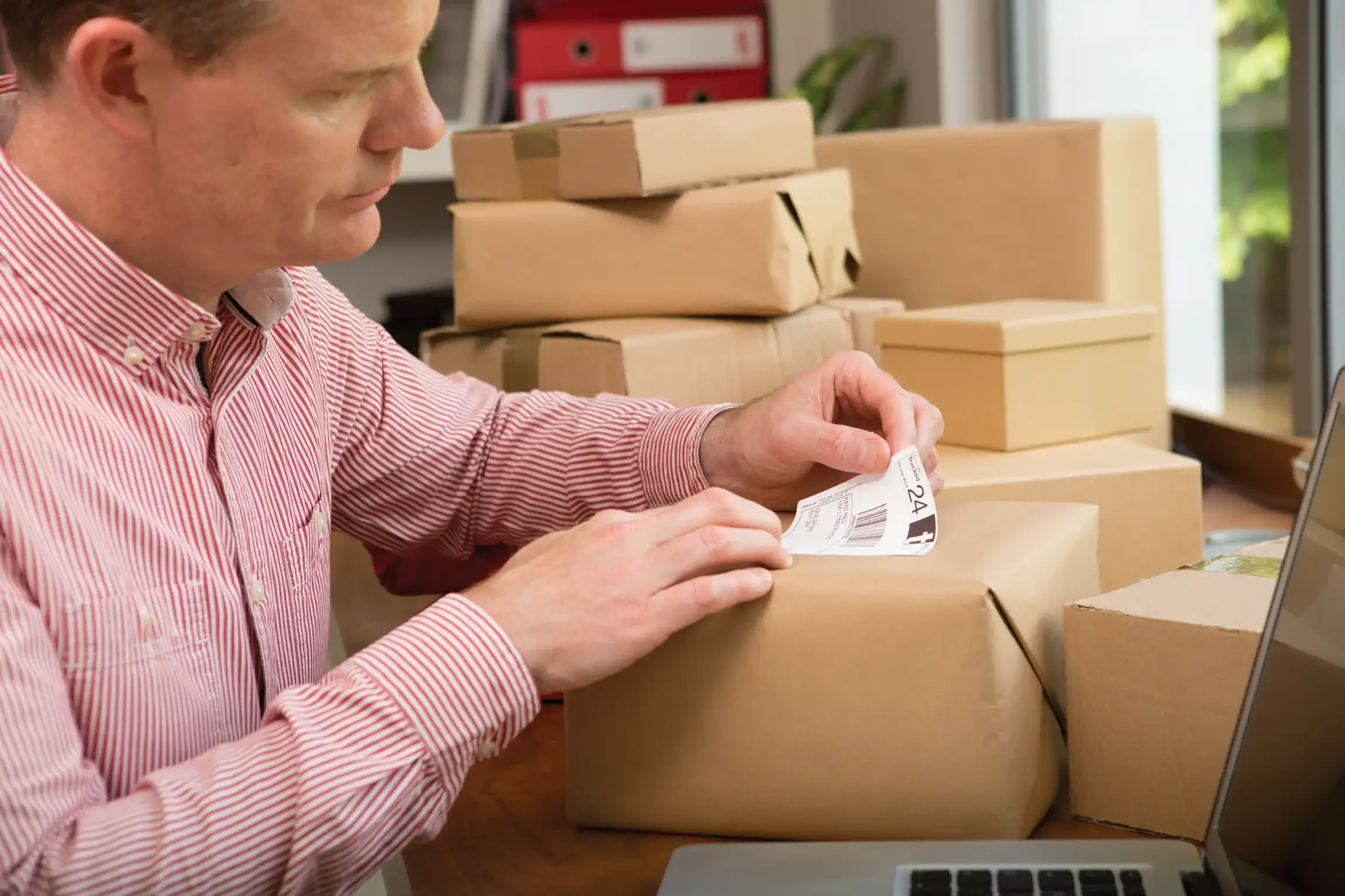 Man adding shipping label to wrapped parcel.