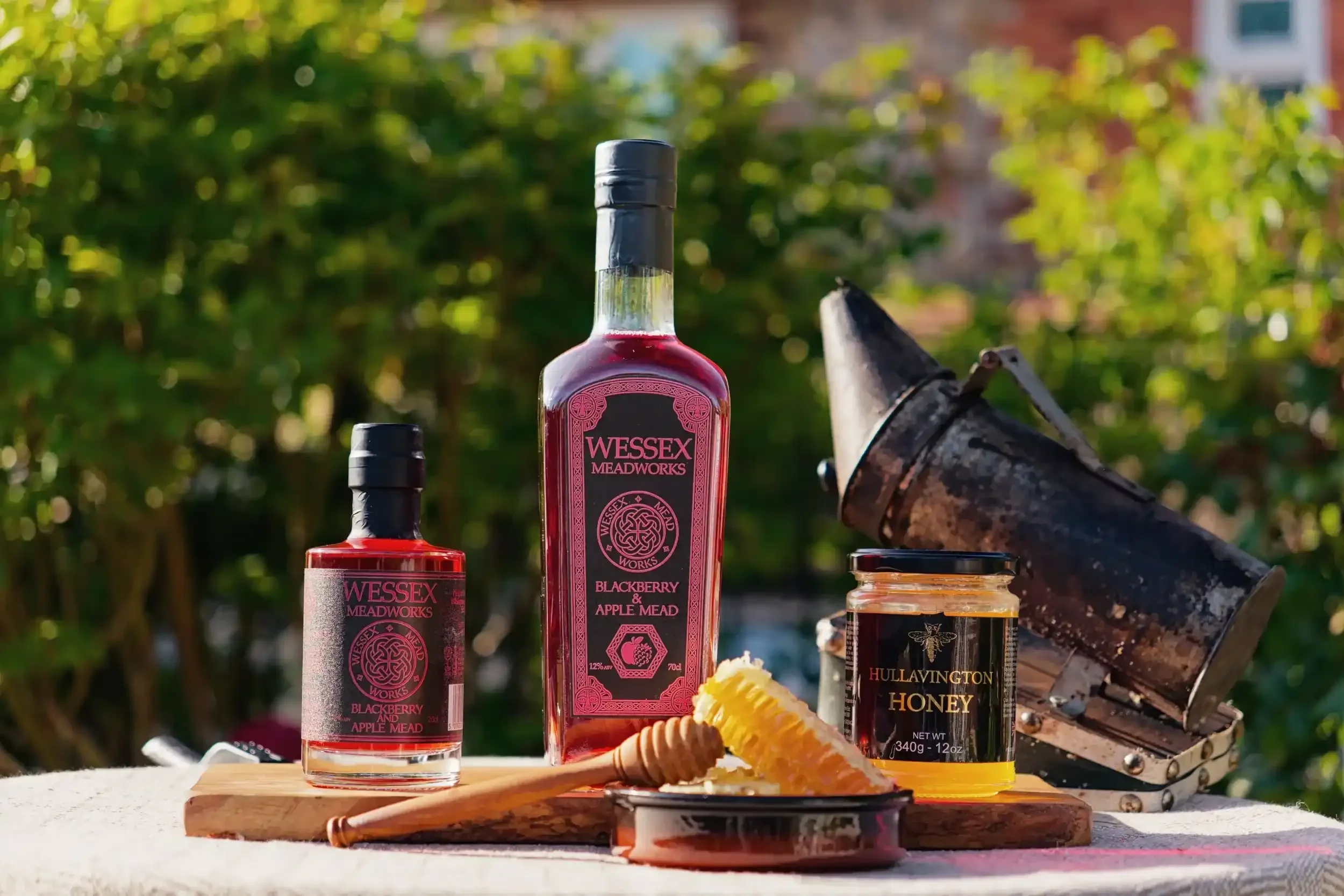 Wessex Meadworks blackberry bottles, jar of honey, dish with honeycomb, beehive smoker