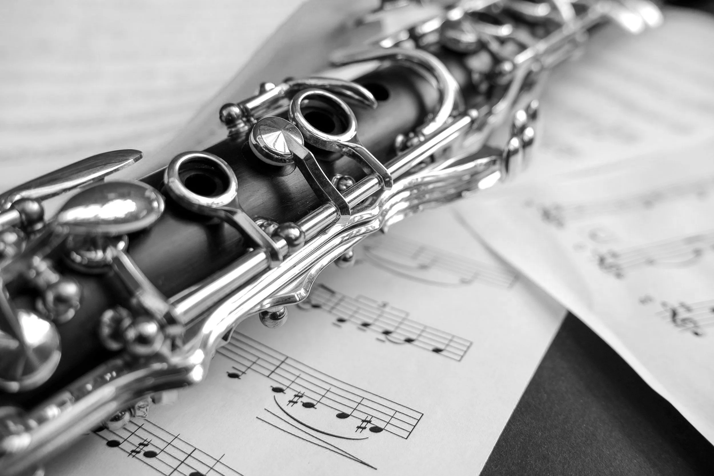 Close-up black and white photo of a musical flute with sheet music underneath.