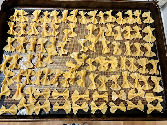 Uncooked pasta shells arranged on a baking sheet lined with parchment paper.