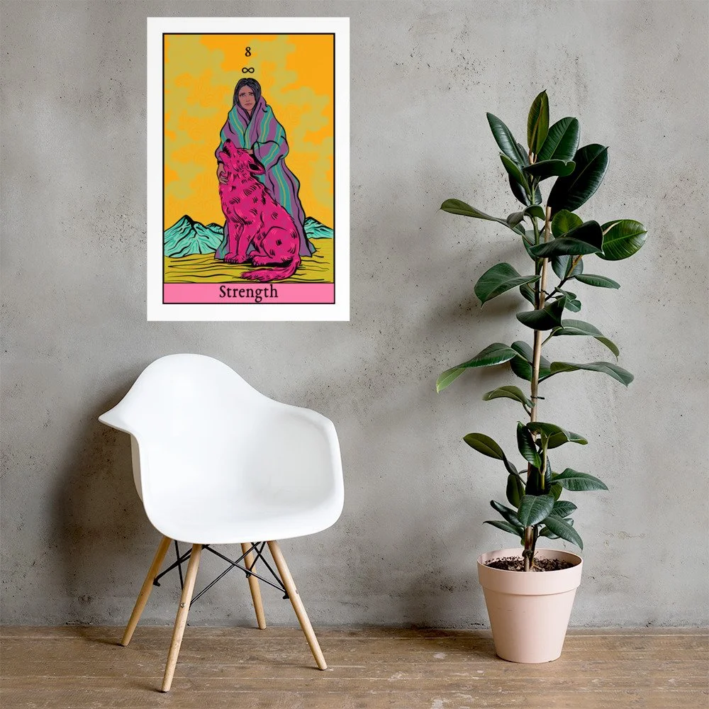 A colorful tarot card titled "Strength" is hung on a gray wall above a white modern chair with wooden legs and a potted rubber plant with dark green leaves.