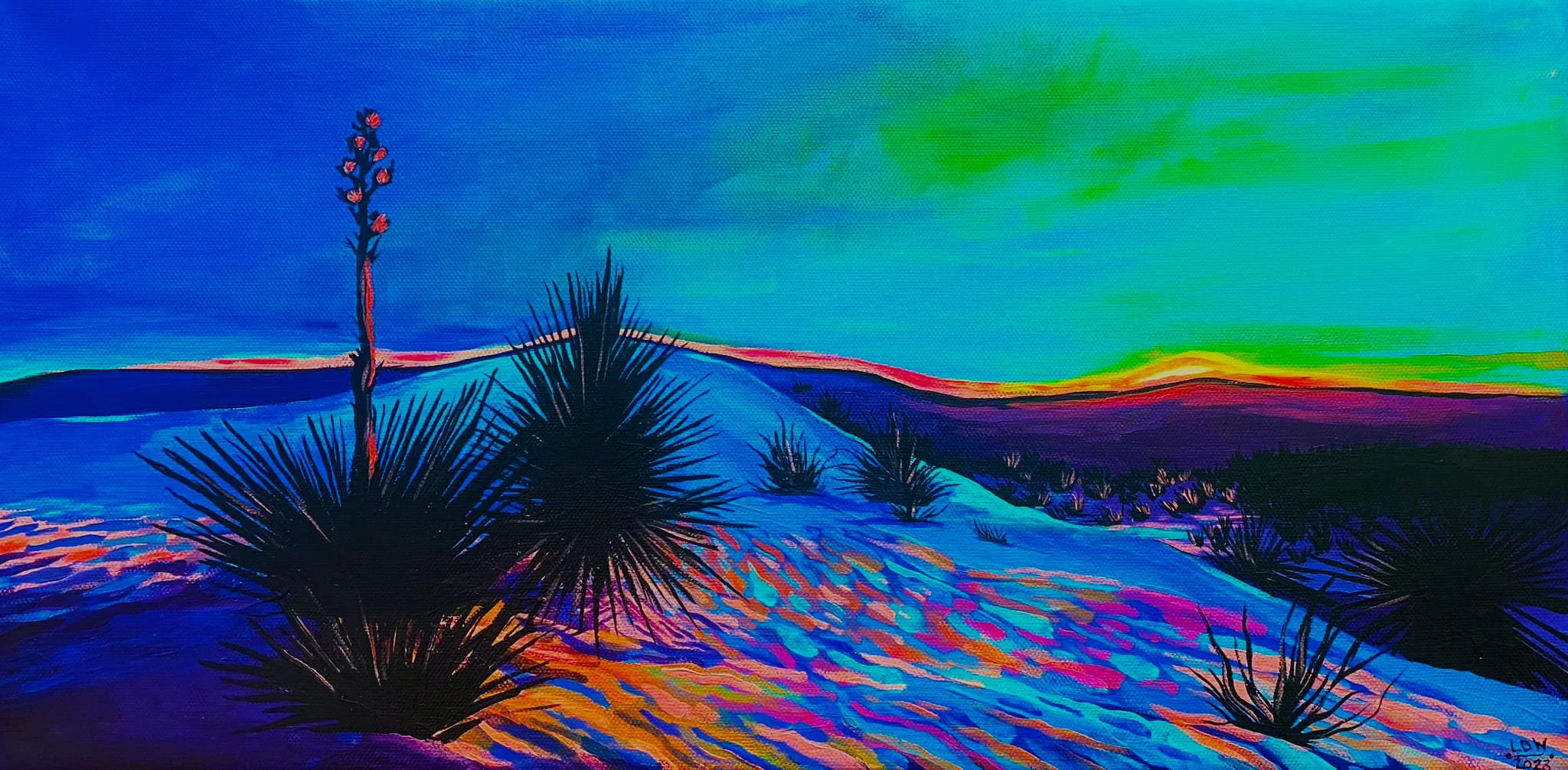 crylic desert landscape showing rolling white sand dunes illuminated in saturated pink, orange, and blue twilight tones, silhouetted yucca plants with tall flowering stalks in the foreground, and a luminous green and blue evening sky over distant mou