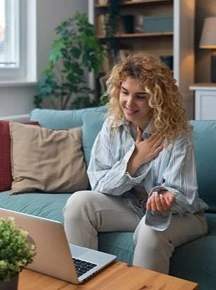 woman in telehealth therapy with hand over heart