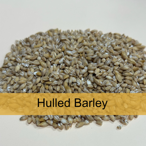 A mound of hulled barley grains on a white background with a label reading 'Hulled Barley' in black text on a yellow background.