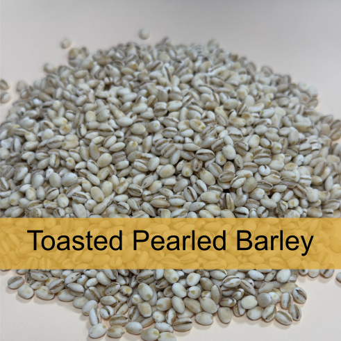 A pile of toasted pearled barley with a label that reads 'Toasted Pearled Barley' in black text on a yellow background.