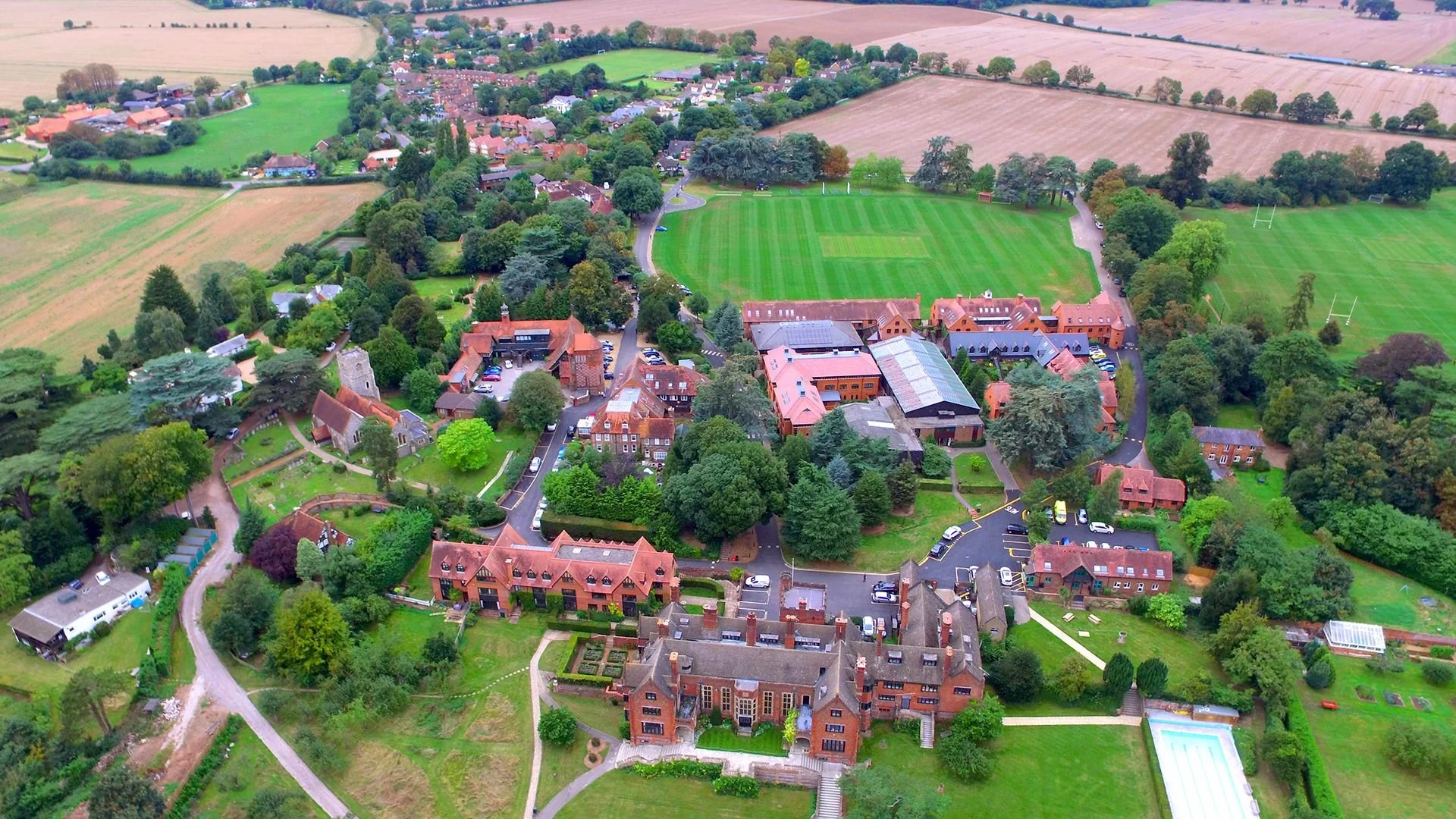 Shiplake large estate and surrounding buildings with lush green lawns, trees, and sports fields in a rural area.