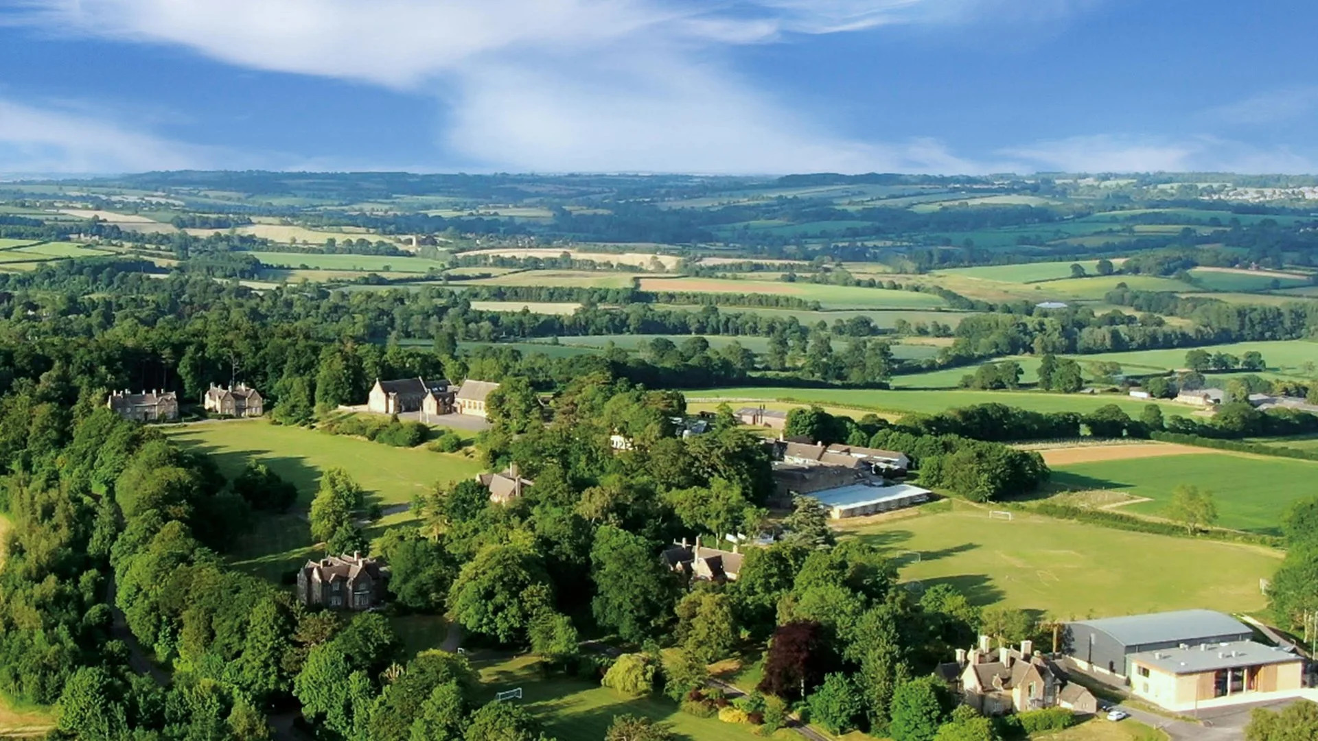 A scenic aerial view of a rural landscape with Kingham Hill School