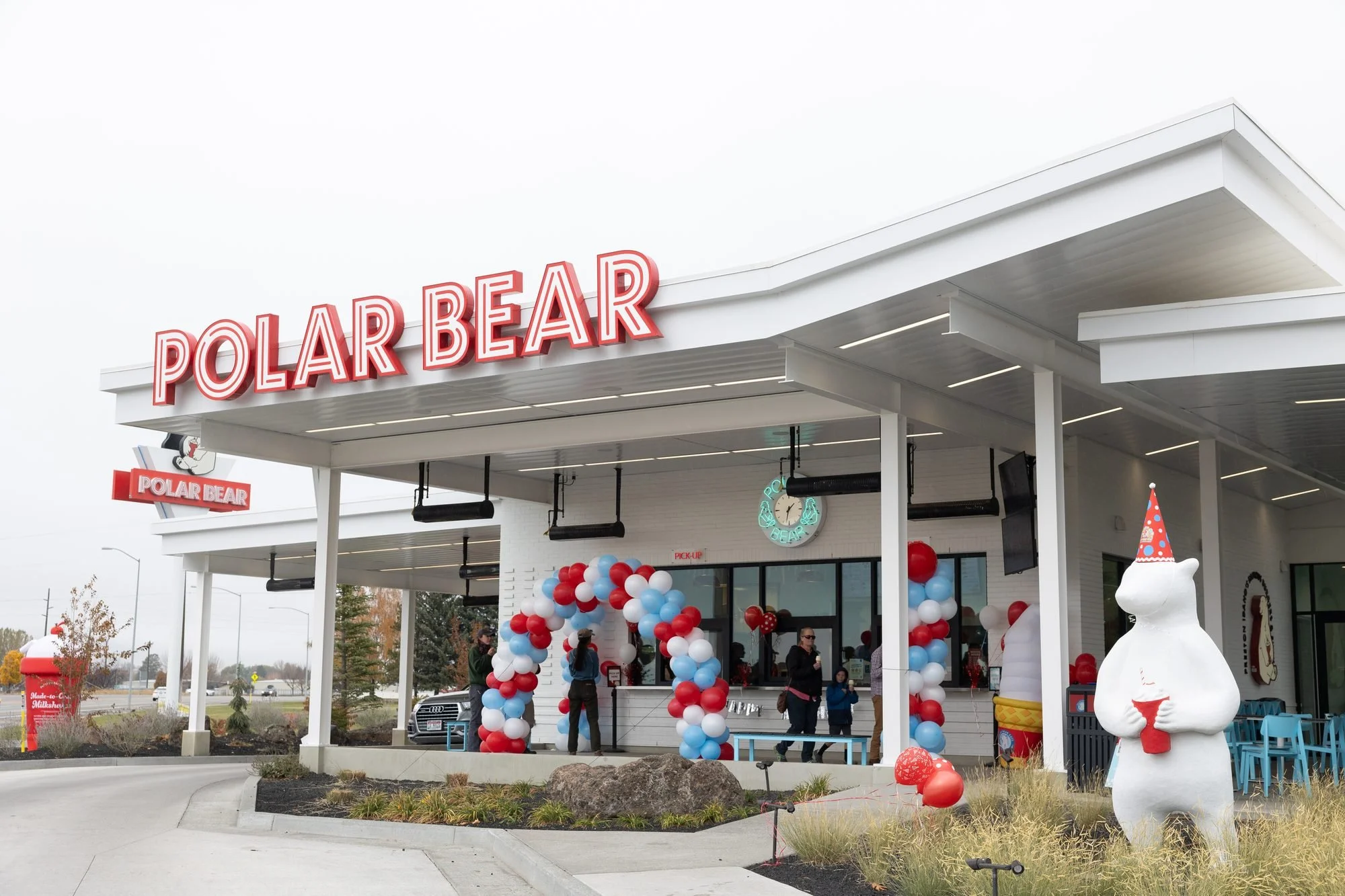 Polar Bear drive-in exterior with red, white and blue balloons and a polar bear statue under an overcast sky