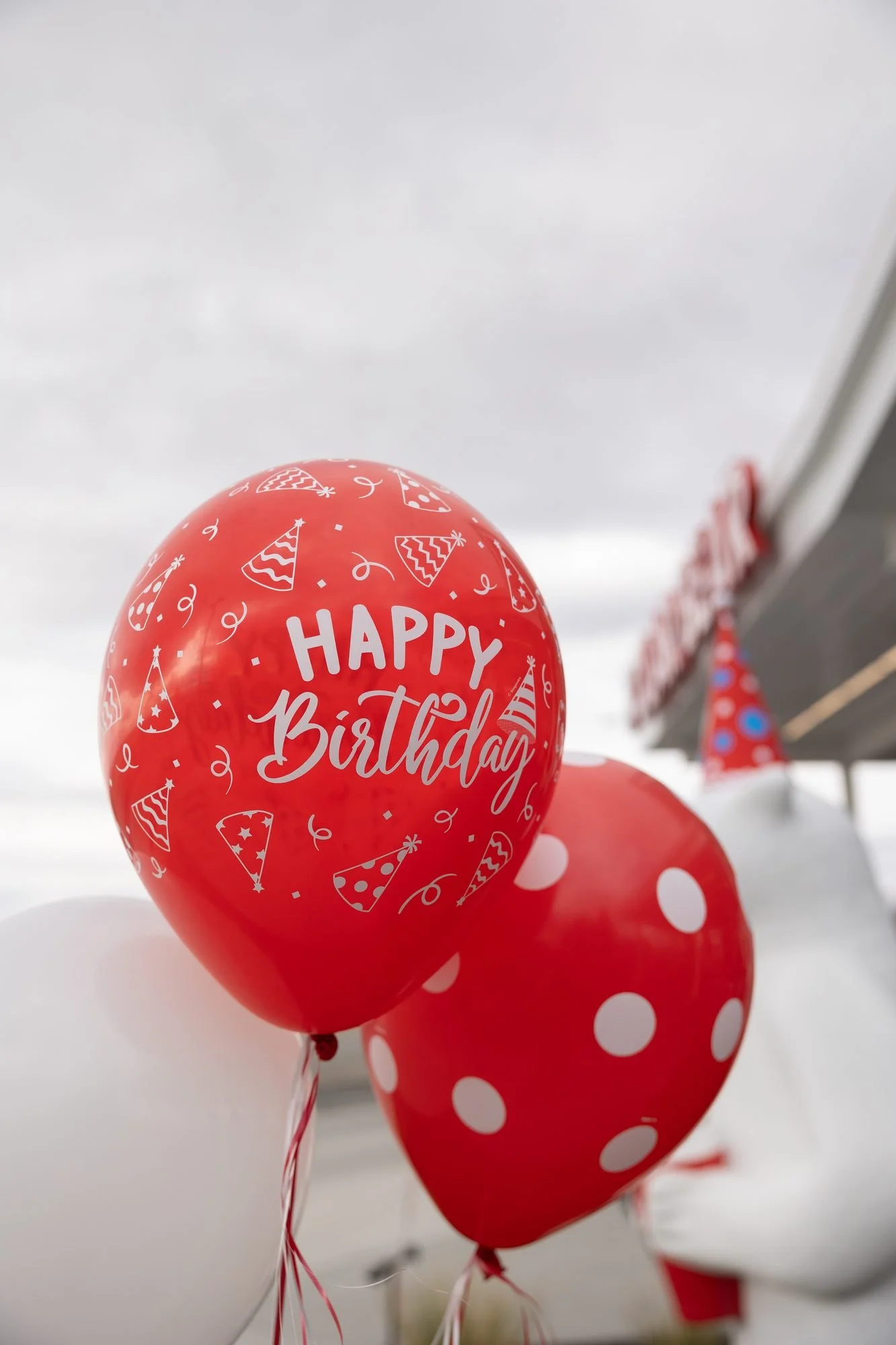 Red balloons printed with Happy Birthday floating in front of a drive-in awning