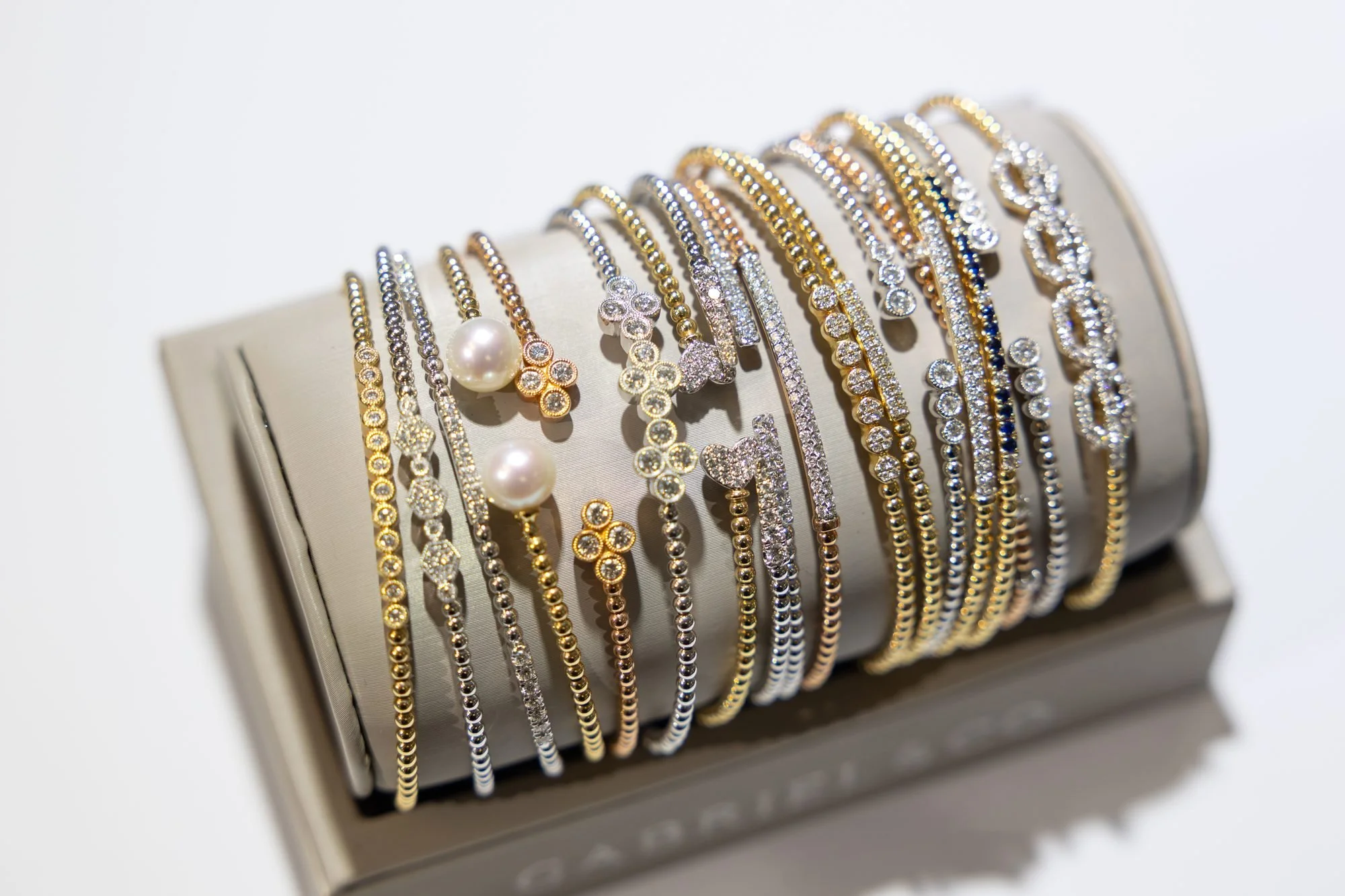 A stack of thin gold and silver bangle bracelets displayed on a fabric cuff in a jewelry store