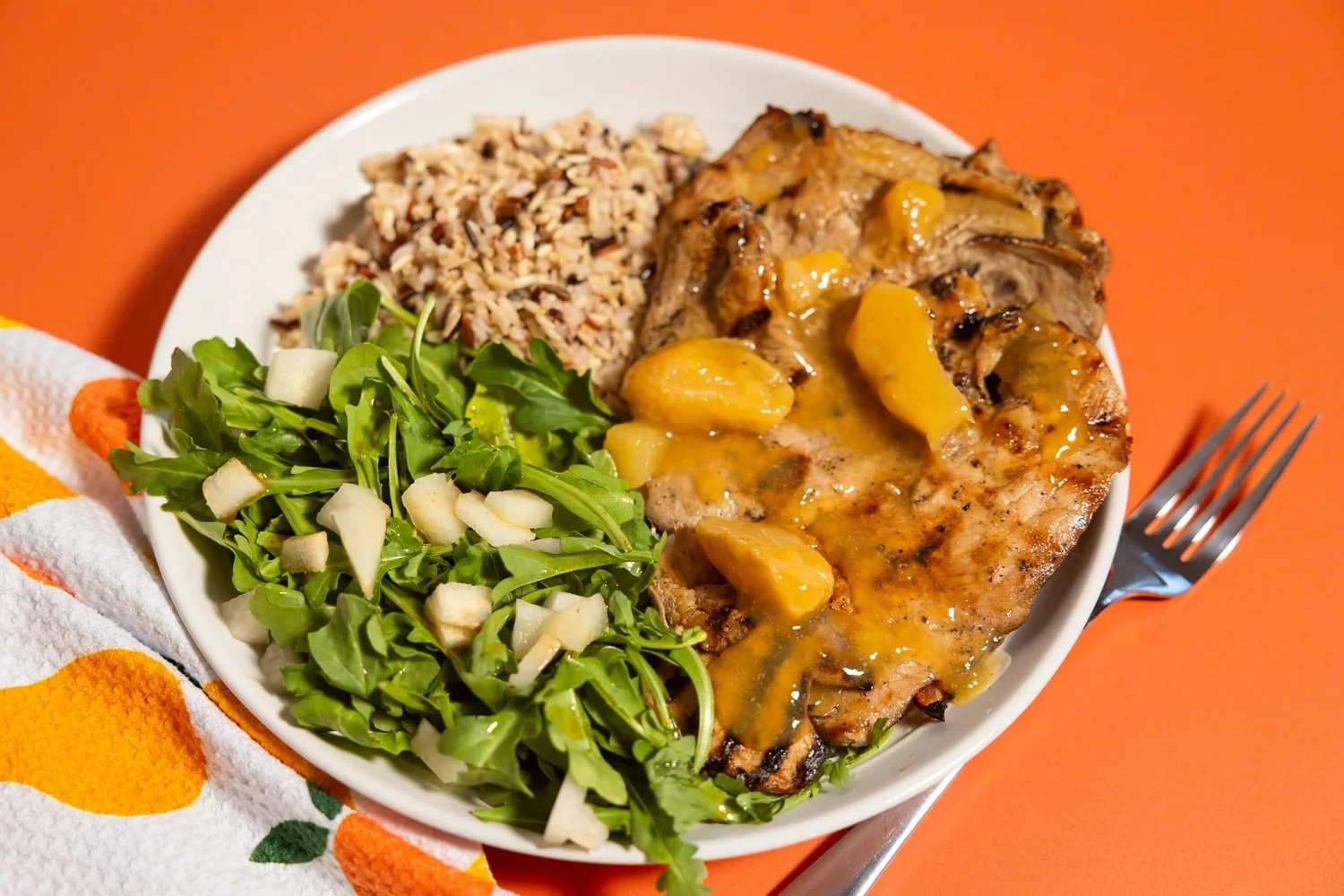 Plate of grilled chicken, rice and arugula on orange, product photo for Citrus Pear in Logan, Utah