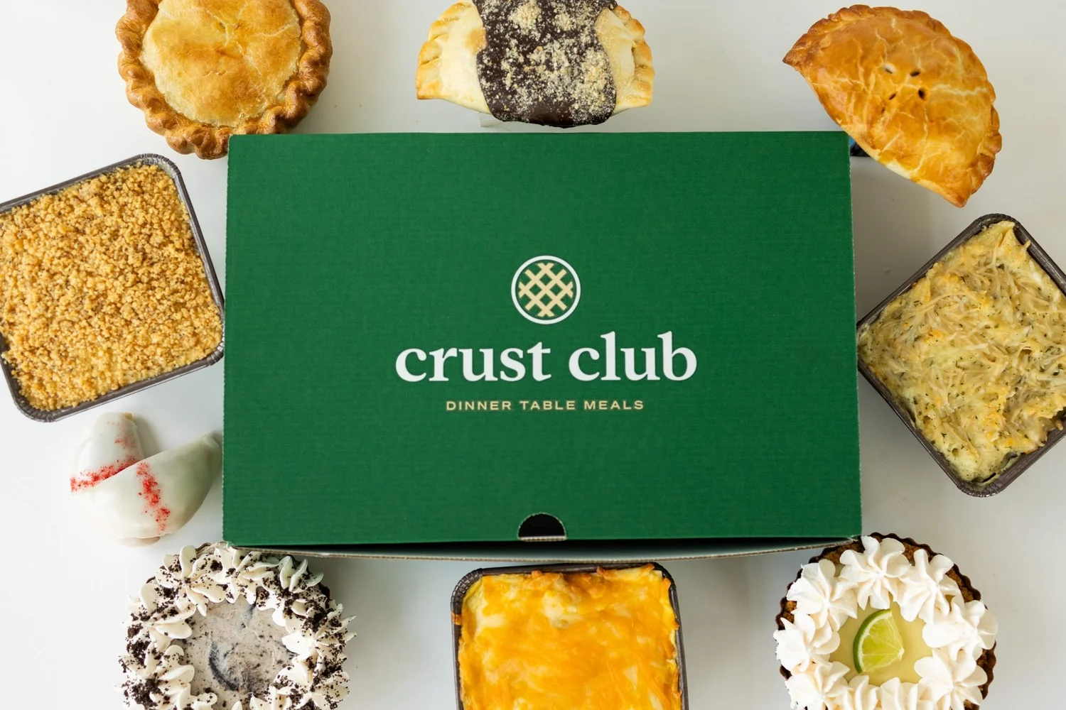 Overhead of a green Crust Club box with casseroles and whole pies around it