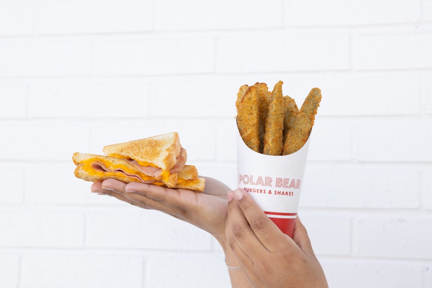 Grilled cheese and fries held up against white tile at Polar Bear in Preston, Idaho