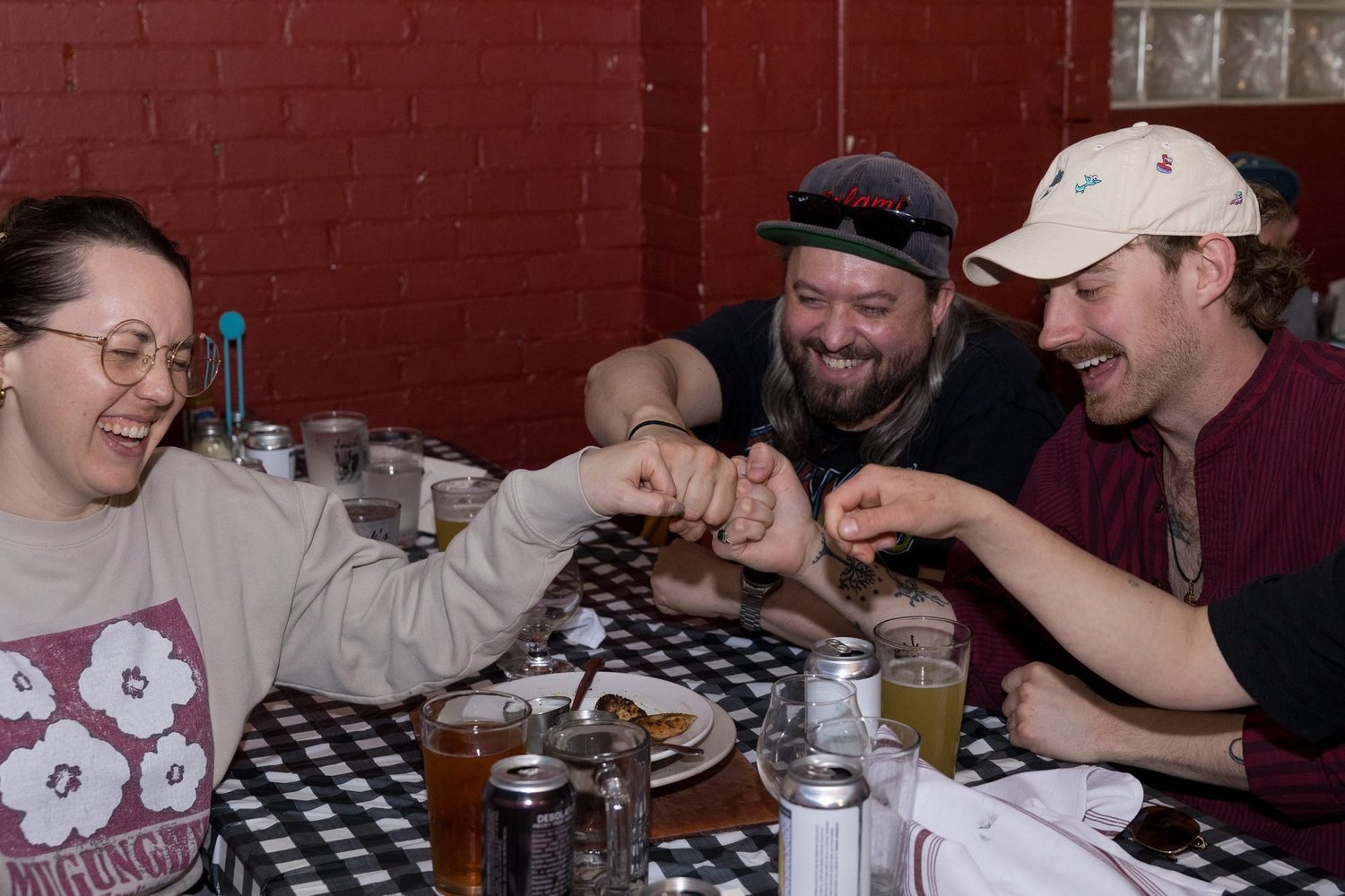 Three friends laughing over pizza at Jack's Wood Fired Oven in Logan, Utah