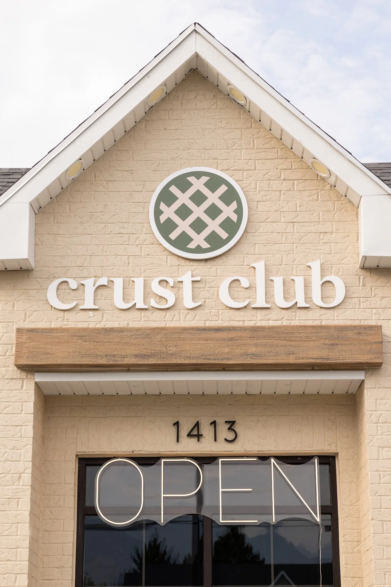 The cream brick Crust Club storefront with its logo and an OPEN sign in the window