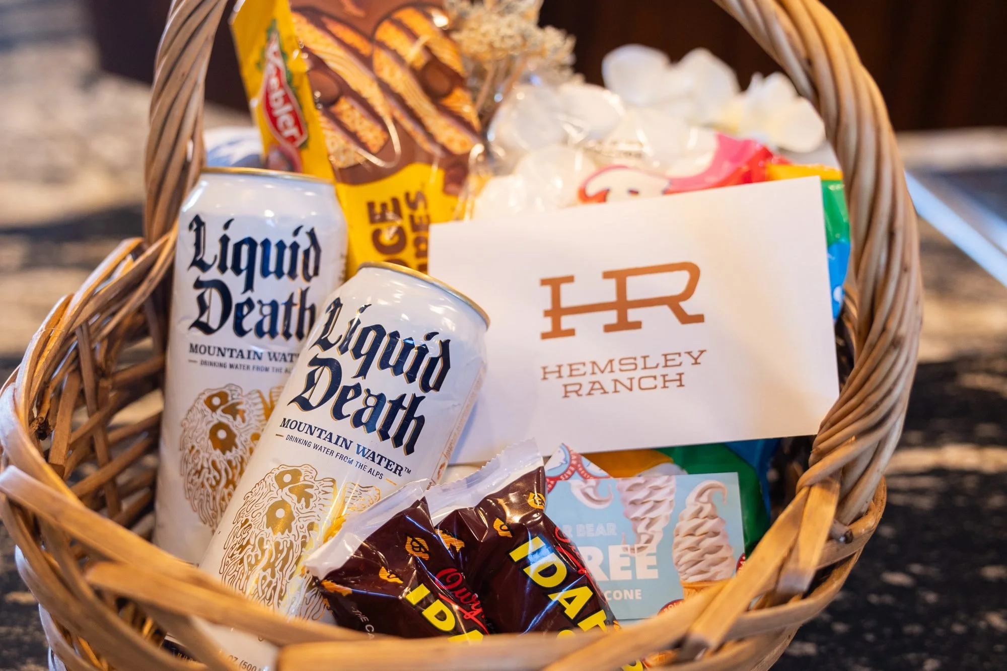 A woven gift basket of canned drinks, snacks and a Hemsley Ranch card