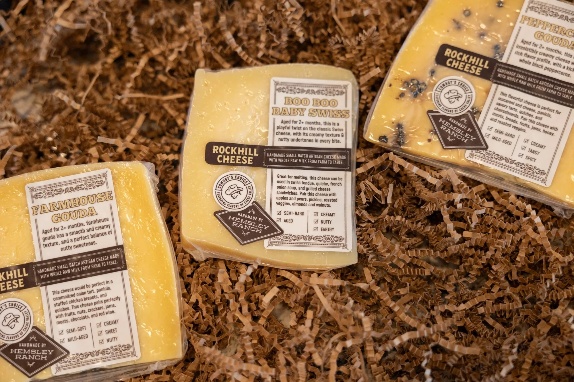 Three wrapped wedges of Rockhill cheese laid on a bed of shredded brown paper
